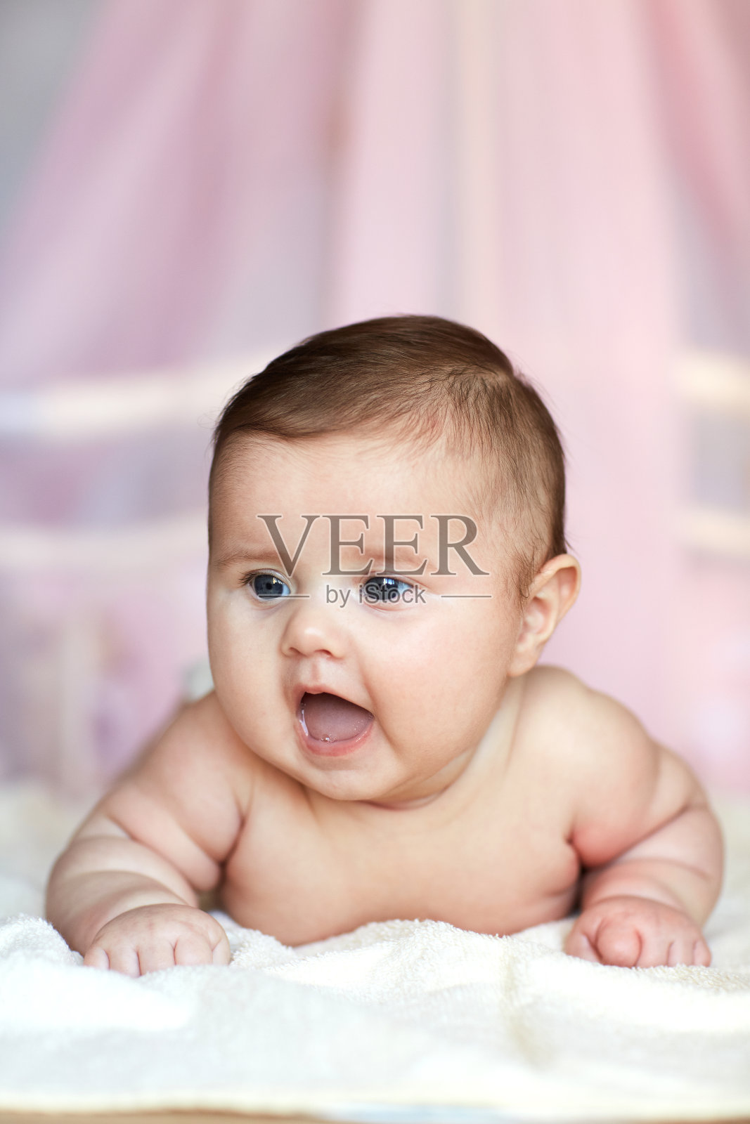 可爱的宝宝趴在床上,看着镜头。照片摄影图片