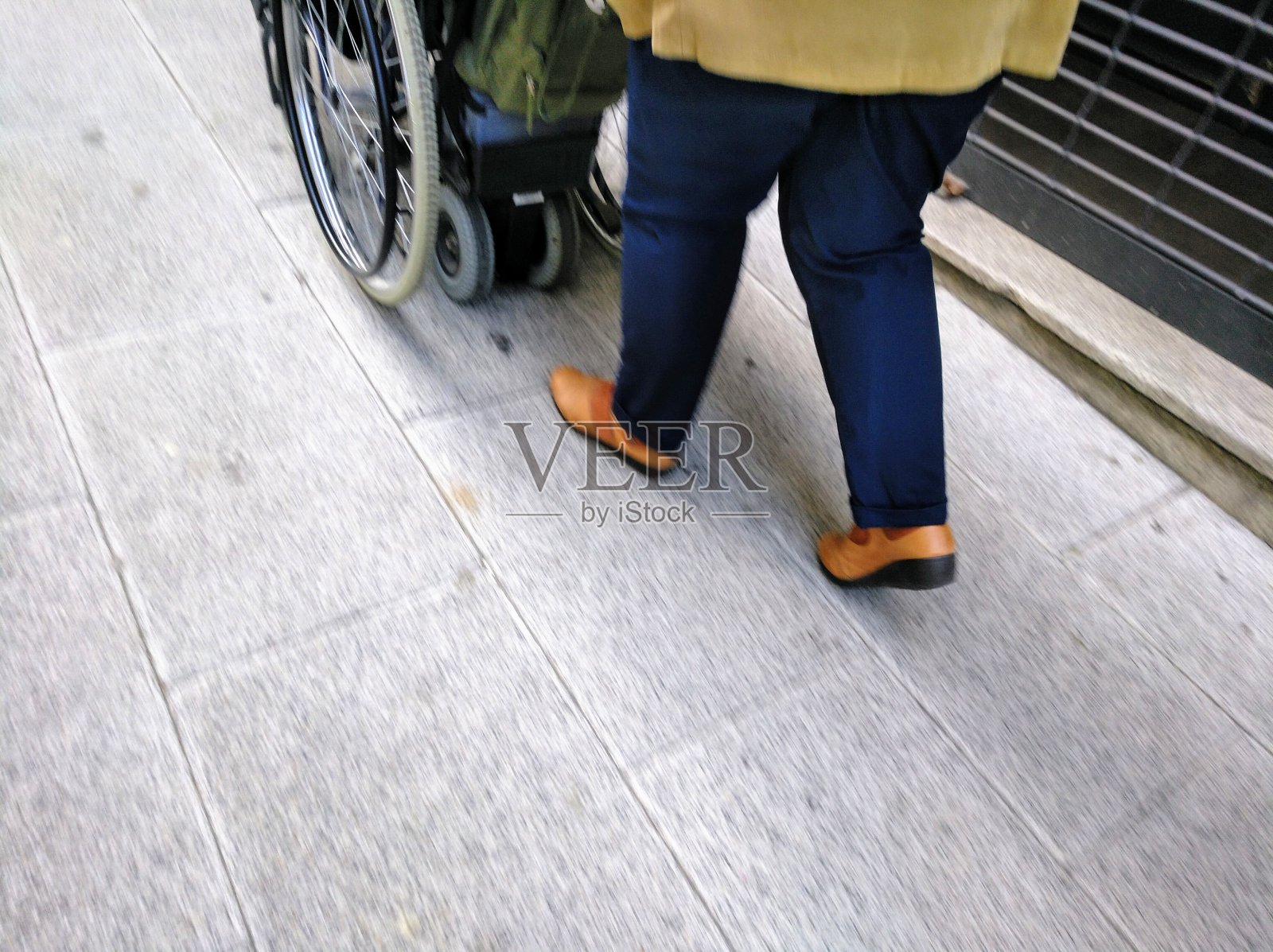 在人行道上推着轮椅的女人。照片摄影图片