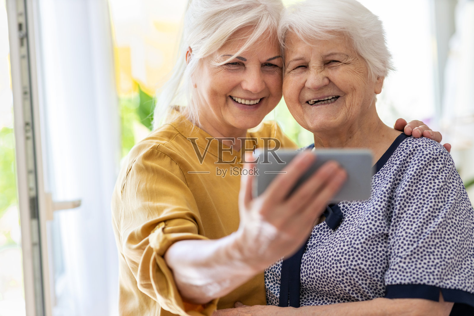 一位年长女性和她成年的女儿一起使用智能手机照片摄影图片