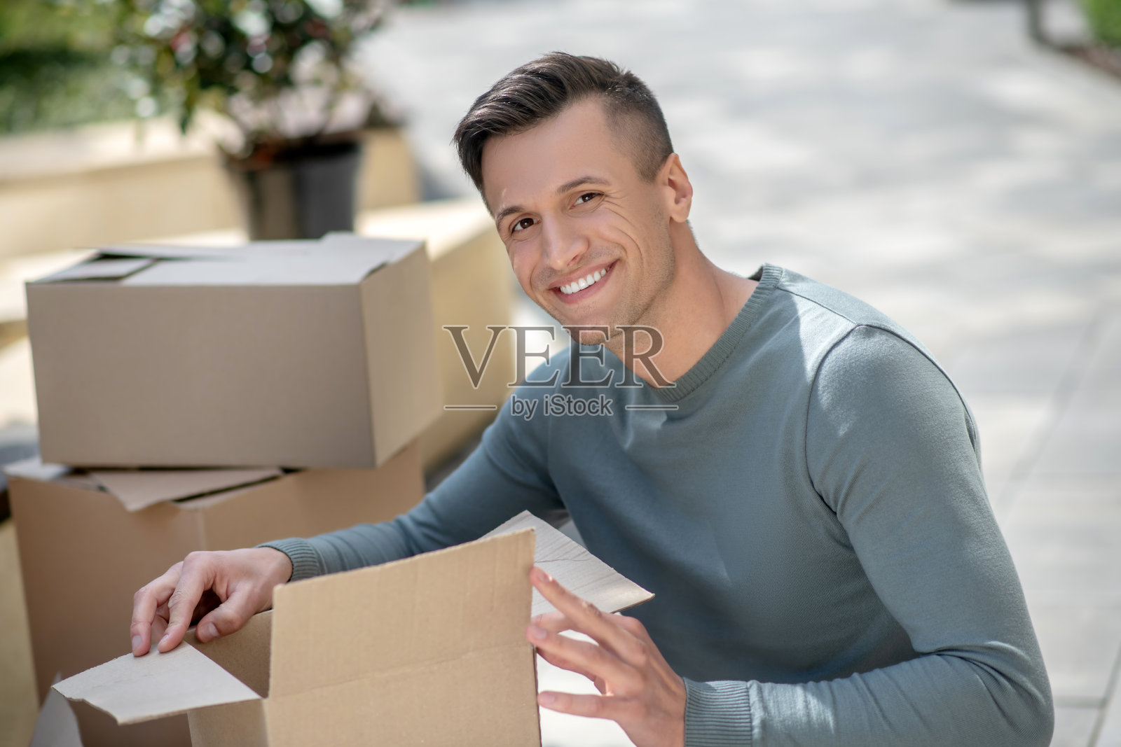 面带微笑的英俊男子坐在纸板旁照片摄影图片