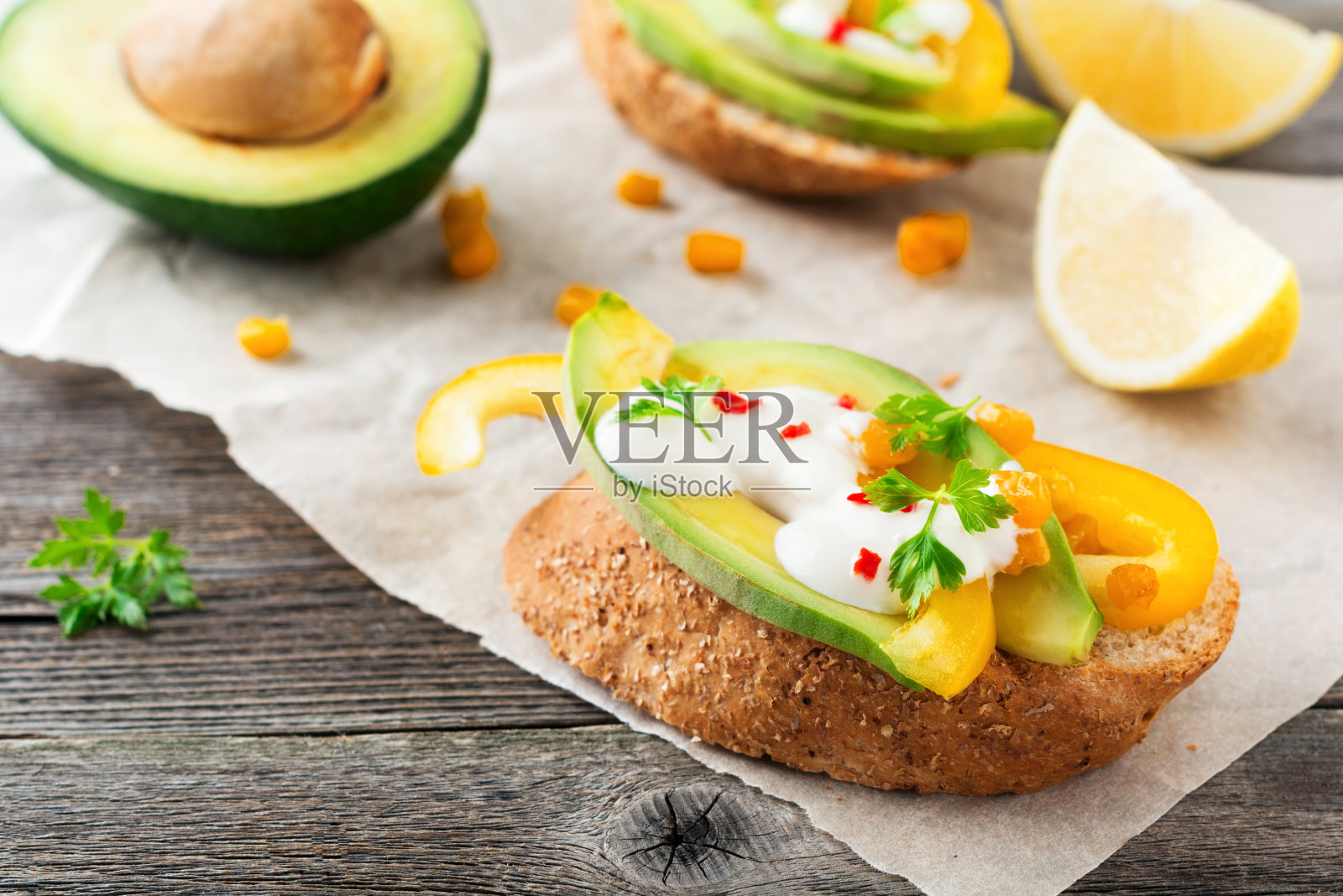 用牛油果、黄椒、玉米粒、欧芹和辣椒做的意式烤面包,在旧的木质背景上。有选择性的重点。照片摄影图片