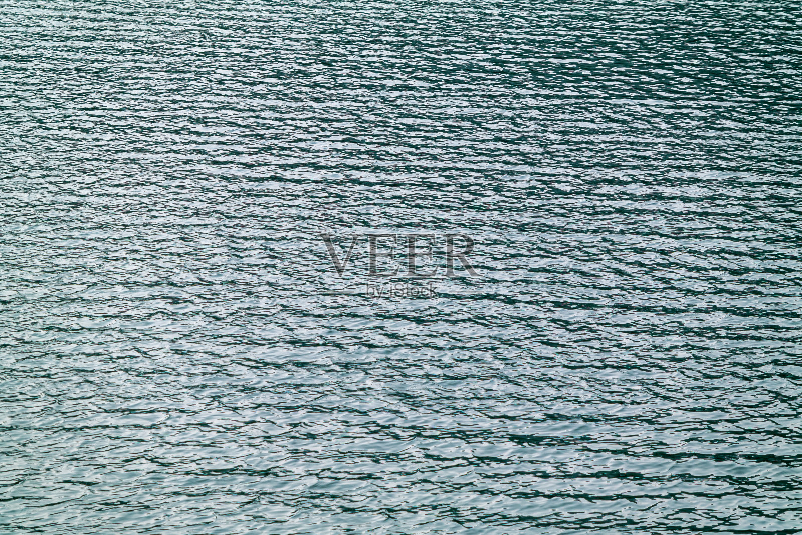 平静的波浪,纹理,和一个美丽的干净的湖的背景。照片摄影图片