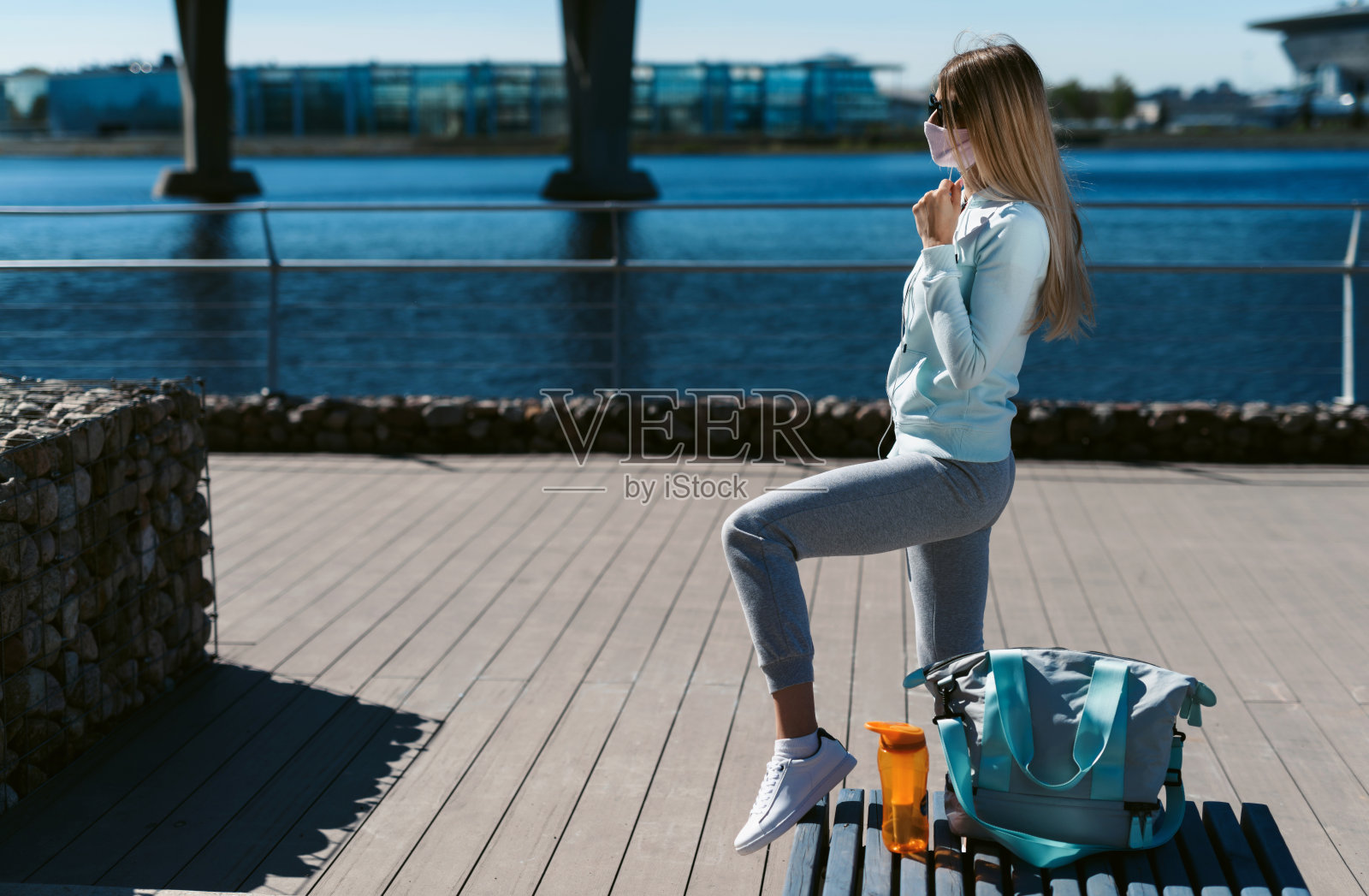 一个年轻的女人戴着防护面具,听着音乐,准备进行街头运动。一个女孩走在现代化的长廊上照片摄影图片