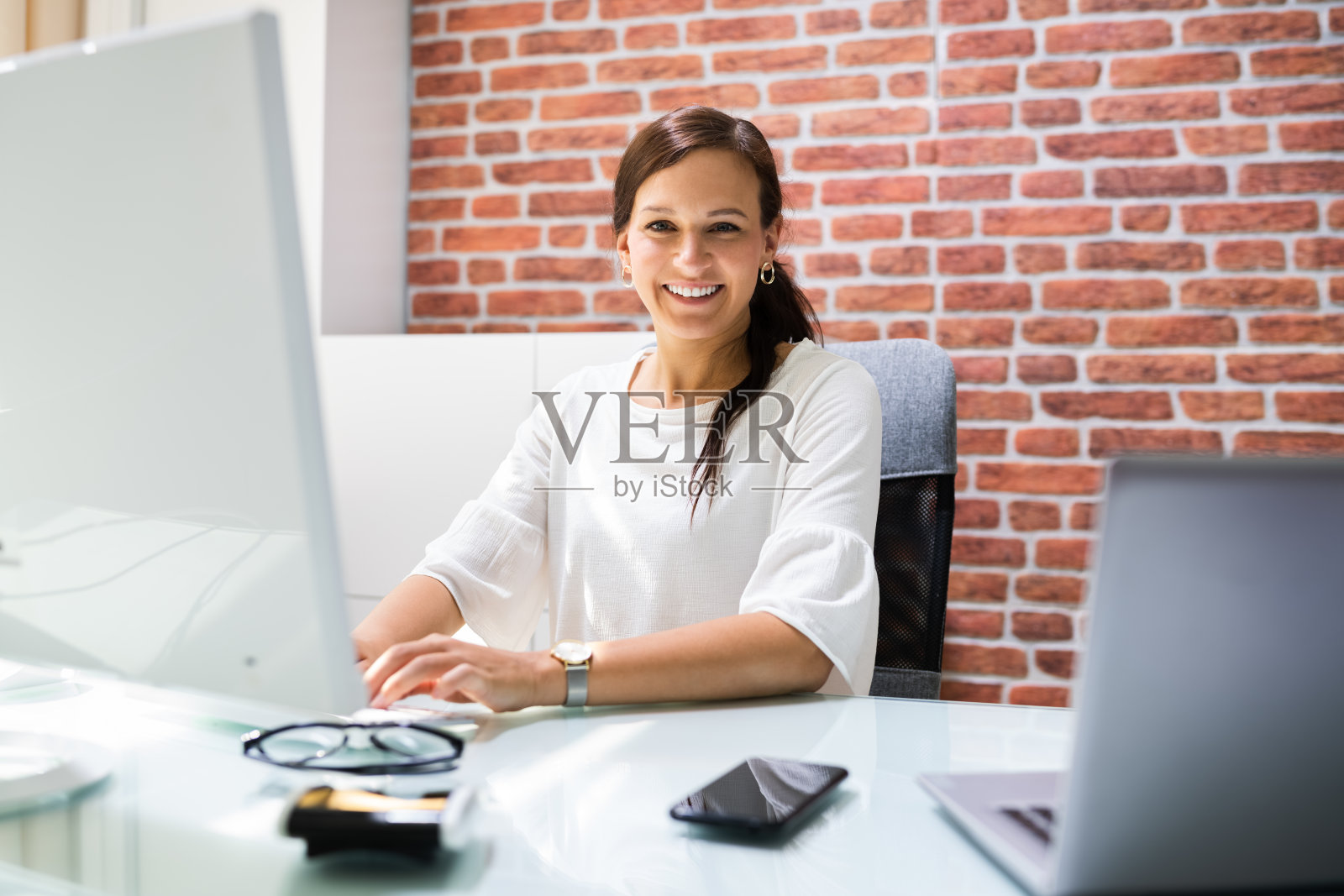 快乐的商务女性在办公桌旁使用电脑照片摄影图片