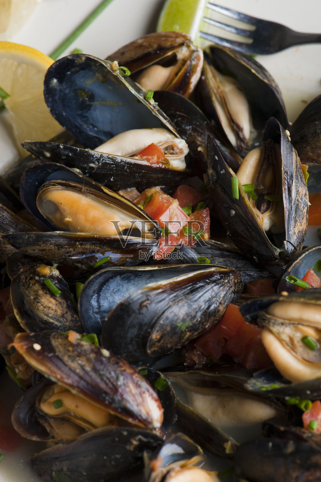 贻贝。经典的法国或美国餐厅的开胃菜:蒸贻贝。用白葡萄酒、黄油、大蒜、洋葱和新鲜香草蒸贝类。配黄油烤法棍面包。照片摄影图片