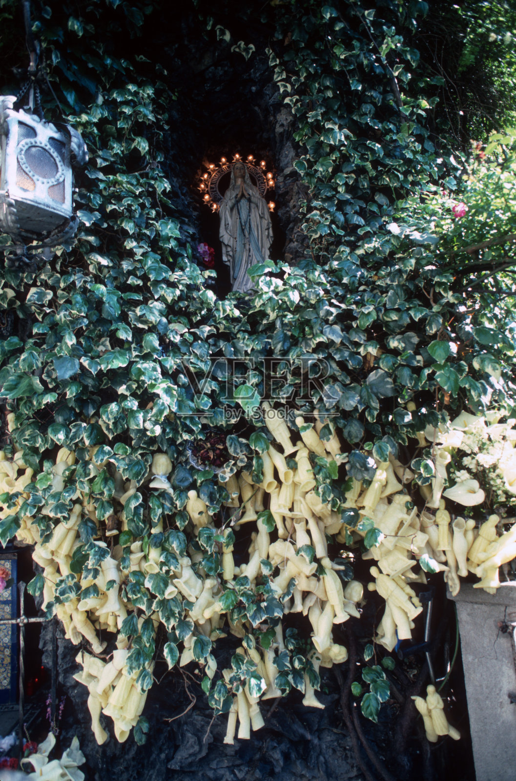 在西班牙加利西亚的维韦罗的概念性修女修道院的卢尔德洞穴中的圣母玛利亚和还愿的供品照片摄影图片