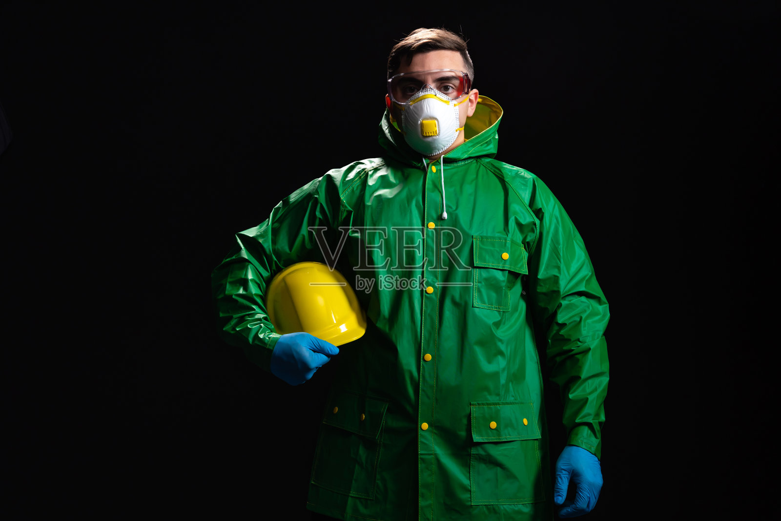 年轻的男工程师或工人的肖像,举着他的头盔在黑色的背景照片摄影图片