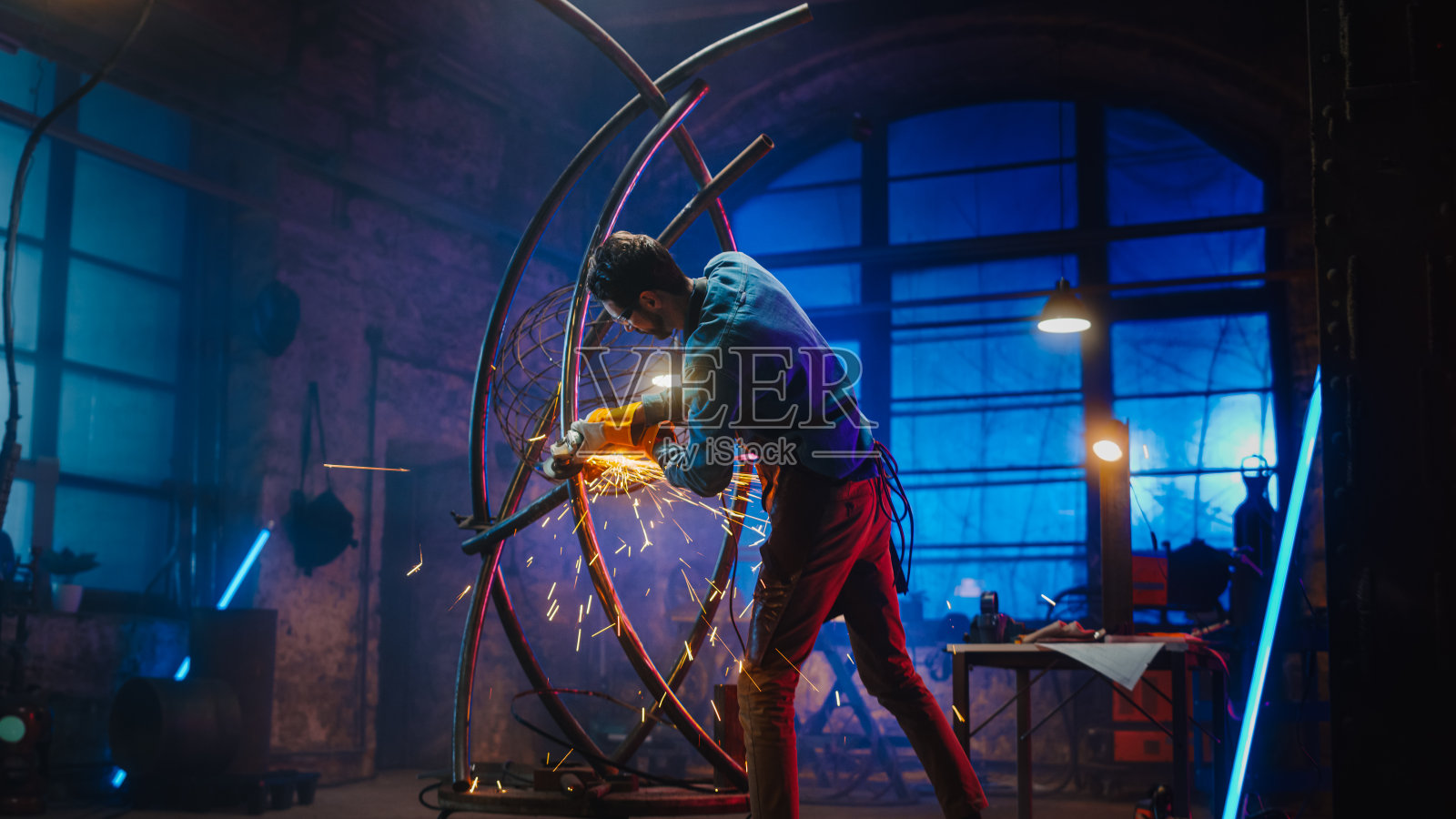 才华横溢的新兴男性艺术家使用圆盘磨床制作一个抽象的,残酷的金属雕塑,反映了现在的时刻。创造现代钢铁艺术的帅哥制造者。照片摄影图片