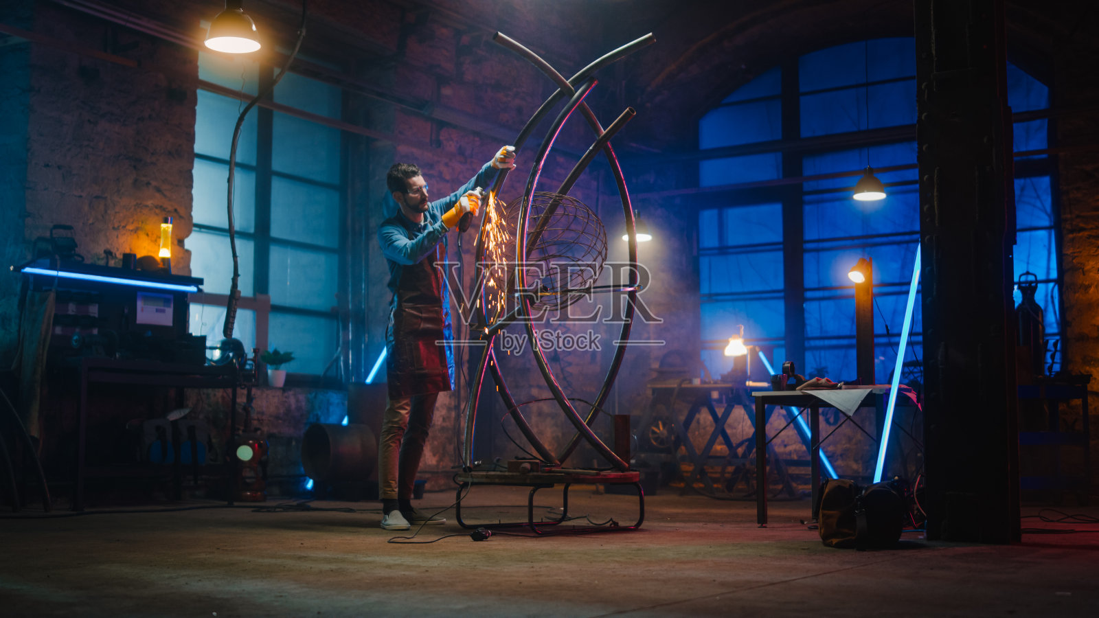 才华横溢的创新艺术家使用角磨床制作一个抽象,野蛮和富有表现力的金属雕塑车间。当代制造者创造现代钢铁艺术。照片摄影图片