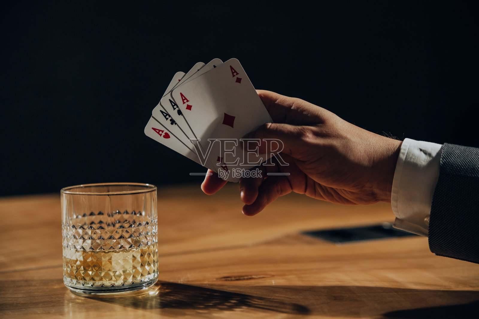 男人打牌和喝威士忌的特写。照片摄影图片