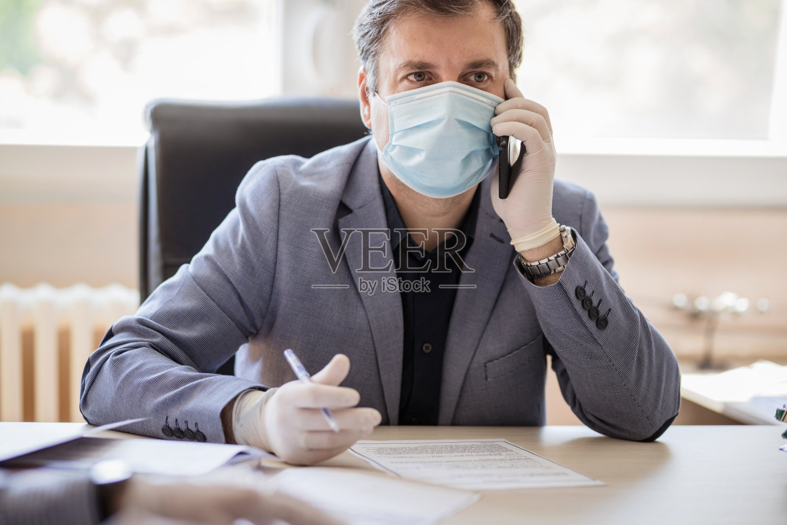 在Covid - 19大流行期间坐在办公室里的商人照片摄影图片