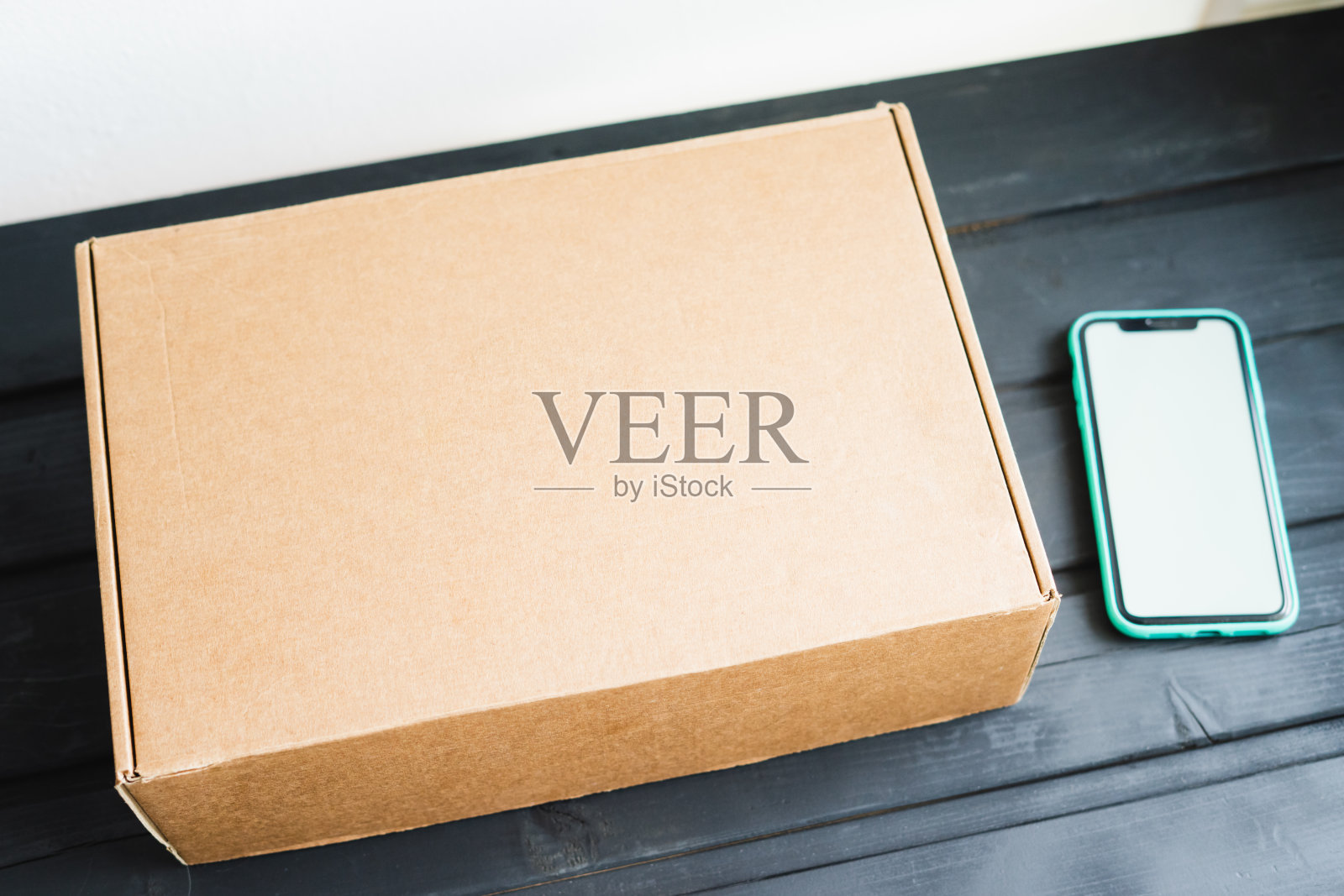 硅胶盒里的工艺品盒和智能手机放在一张黑色木桌上。网上购物照片摄影图片