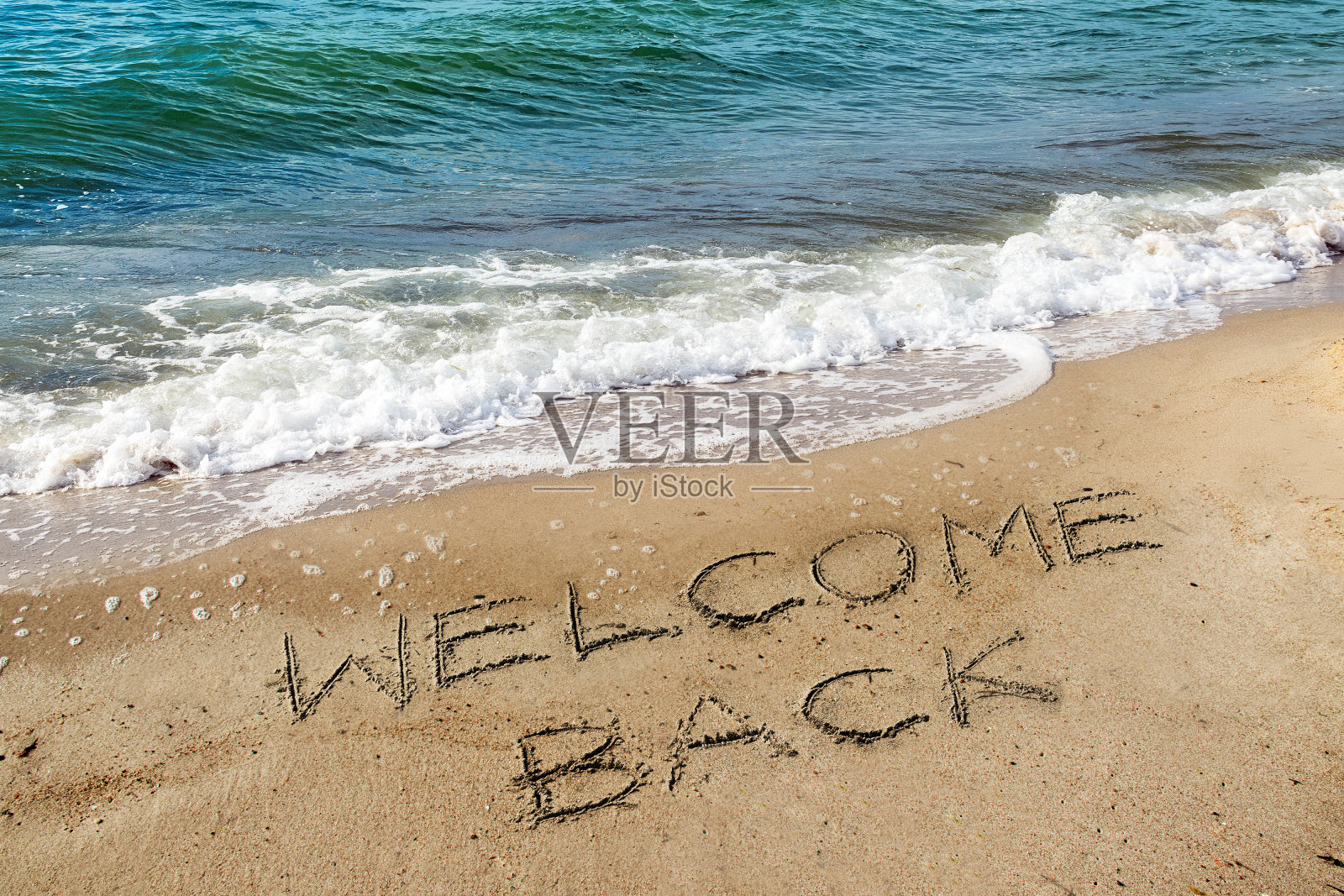 沙滩上写着“欢迎回来”的字样,新冠肺炎疫情后重新开放,海上度假再次成为可能照片摄影图片