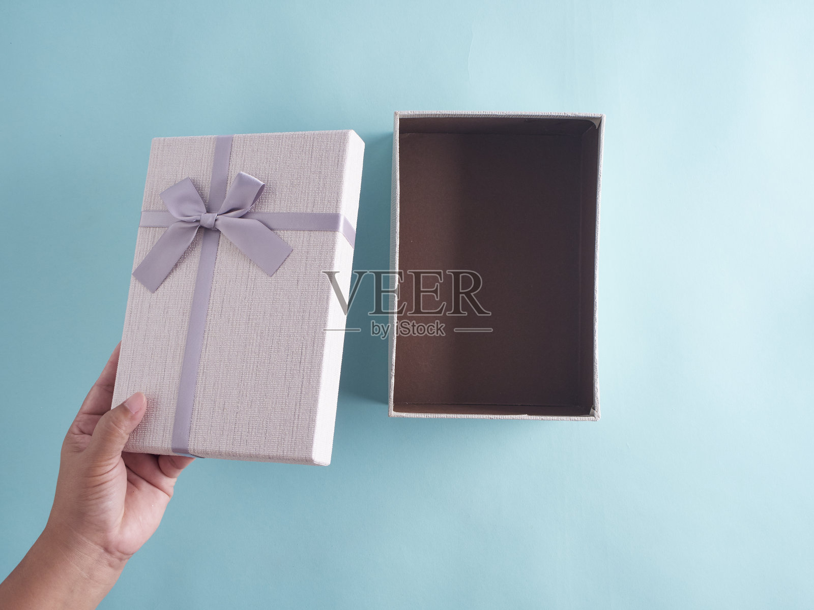 手打开礼物盒在浅蓝色的背景。照片摄影图片