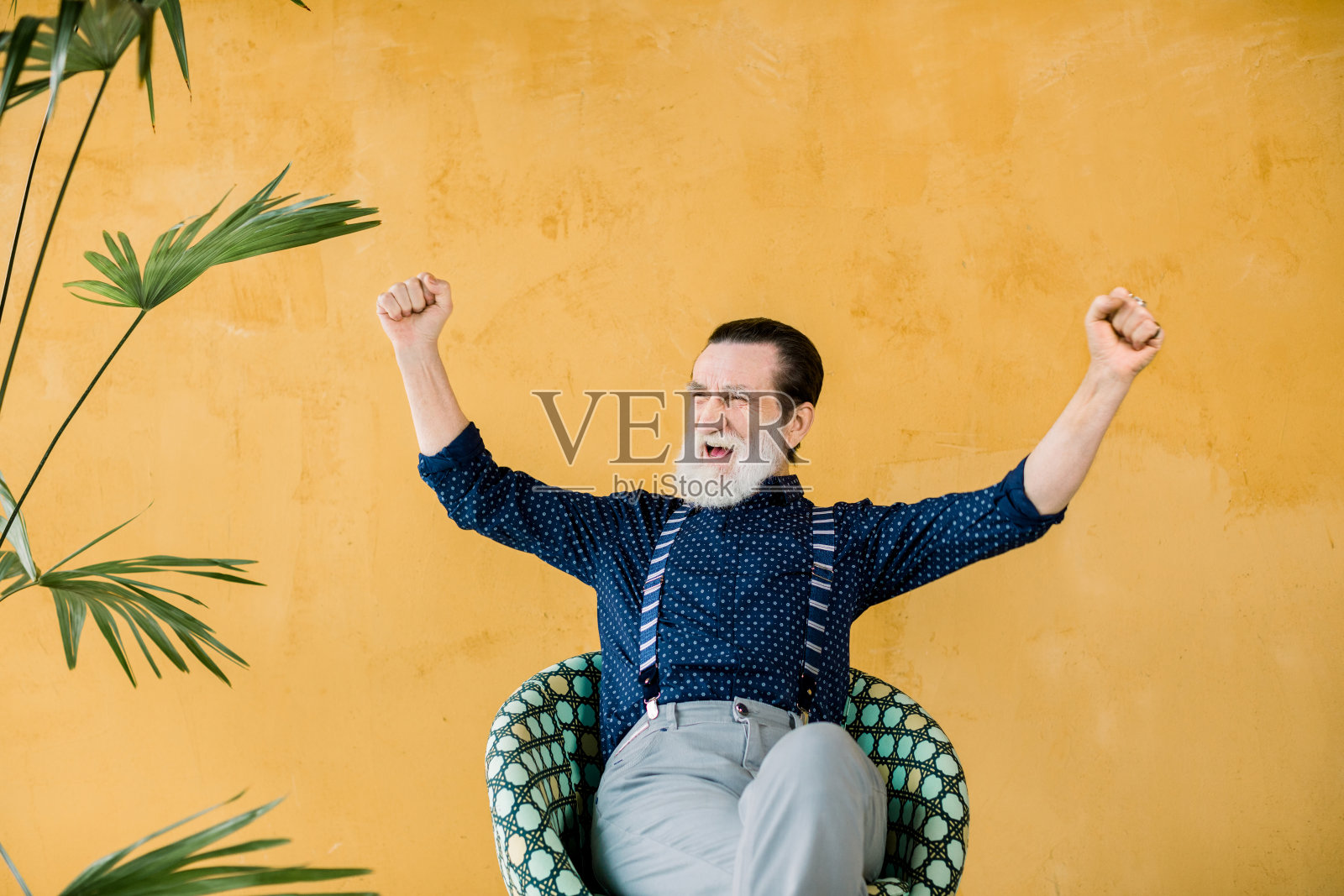 欢快时尚的虚拟现实耳机坐在椅子上的黄色墙壁背景和工作在想象的屏幕上照片摄影图片