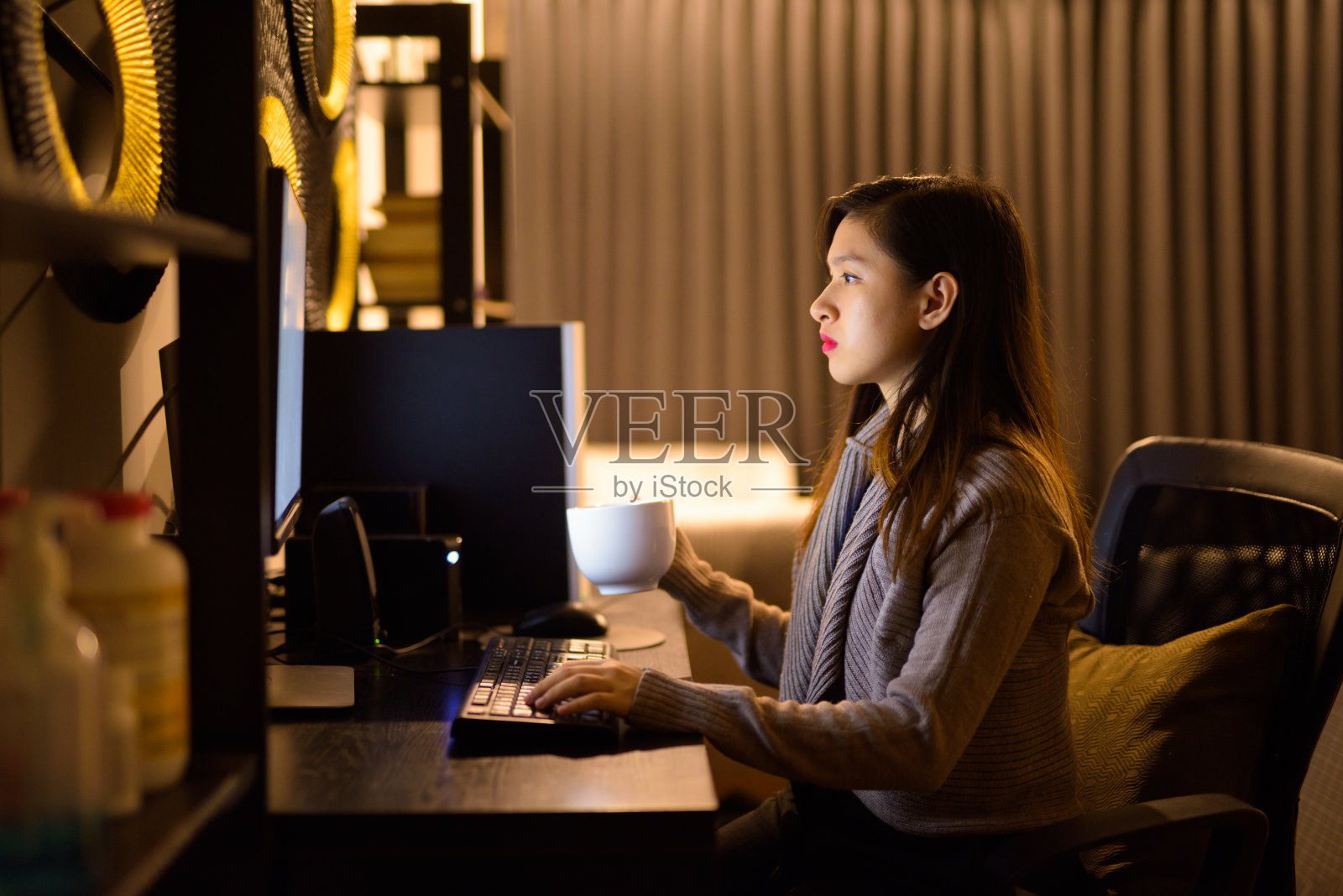 年轻的亚洲女性晚上在家工作的时候喝咖啡照片摄影图片