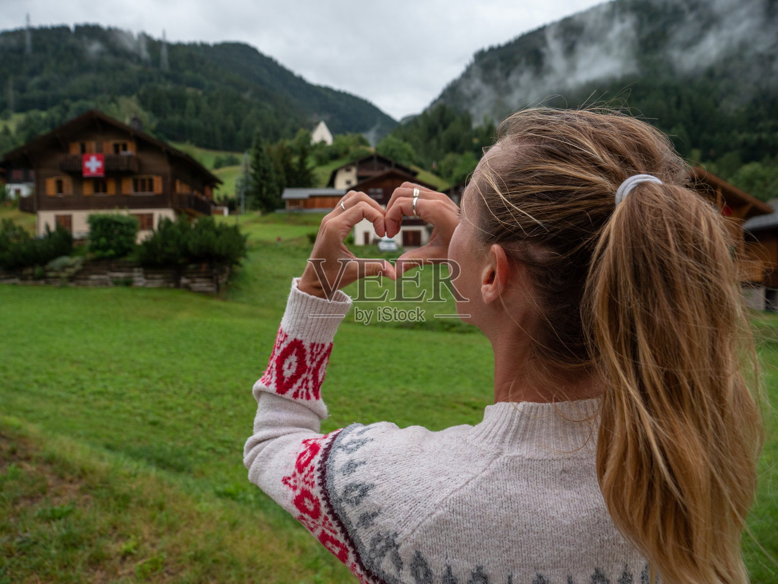 在瑞士村庄里,一名妇女双手制作心形框架照片摄影图片