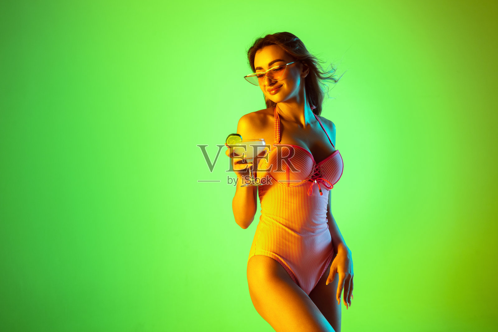 美丽的女孩在时尚的泳衣孤立在霓虹灯梯度工作室背景。夏季,度假,时尚和周末的概念照片摄影图片