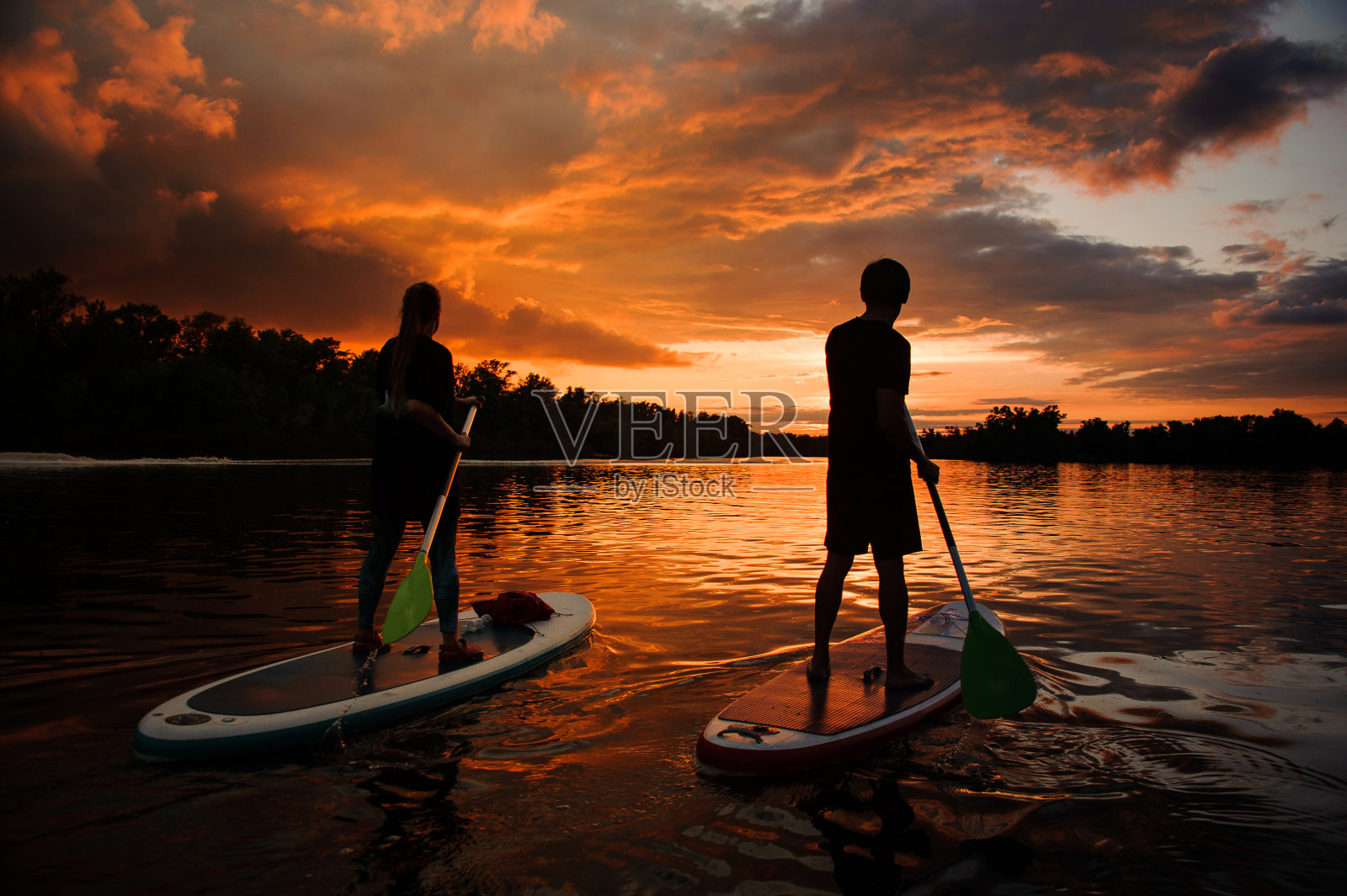 日落时分,几个人在河上冲浪照片摄影图片