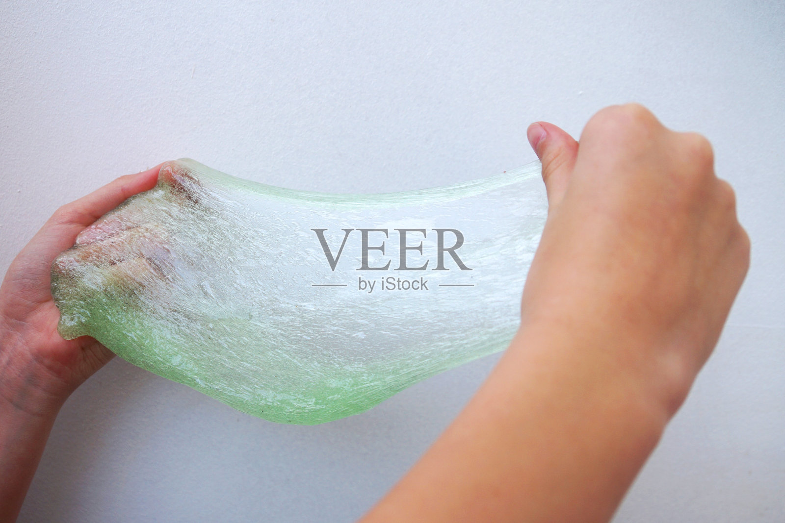 孩子们的手在伸展着绿色的粘液。照片摄影图片