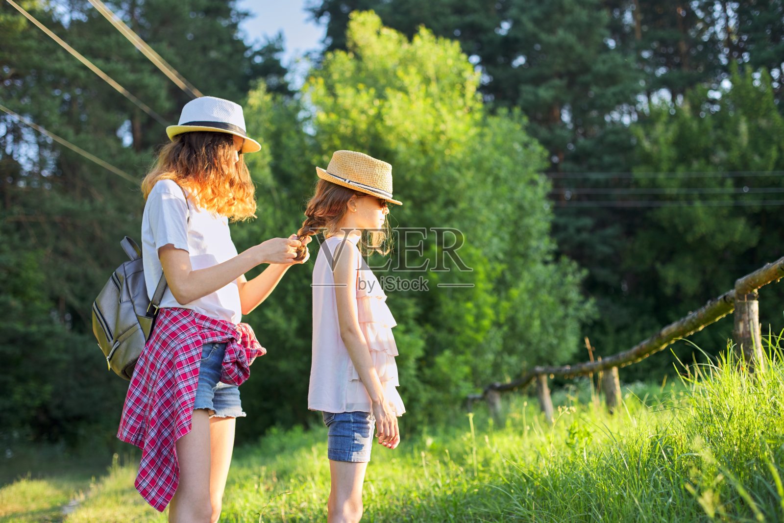 夏天,快乐的孩子们走着享受大自然的假期,姐姐编着妹妹的辫子照片摄影图片