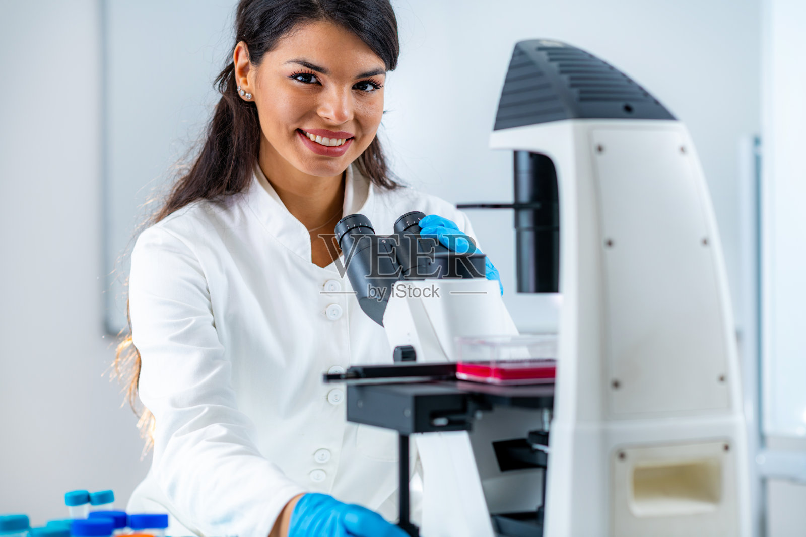 实验室女学生,在显微镜观察台上放置培养瓶照片摄影图片