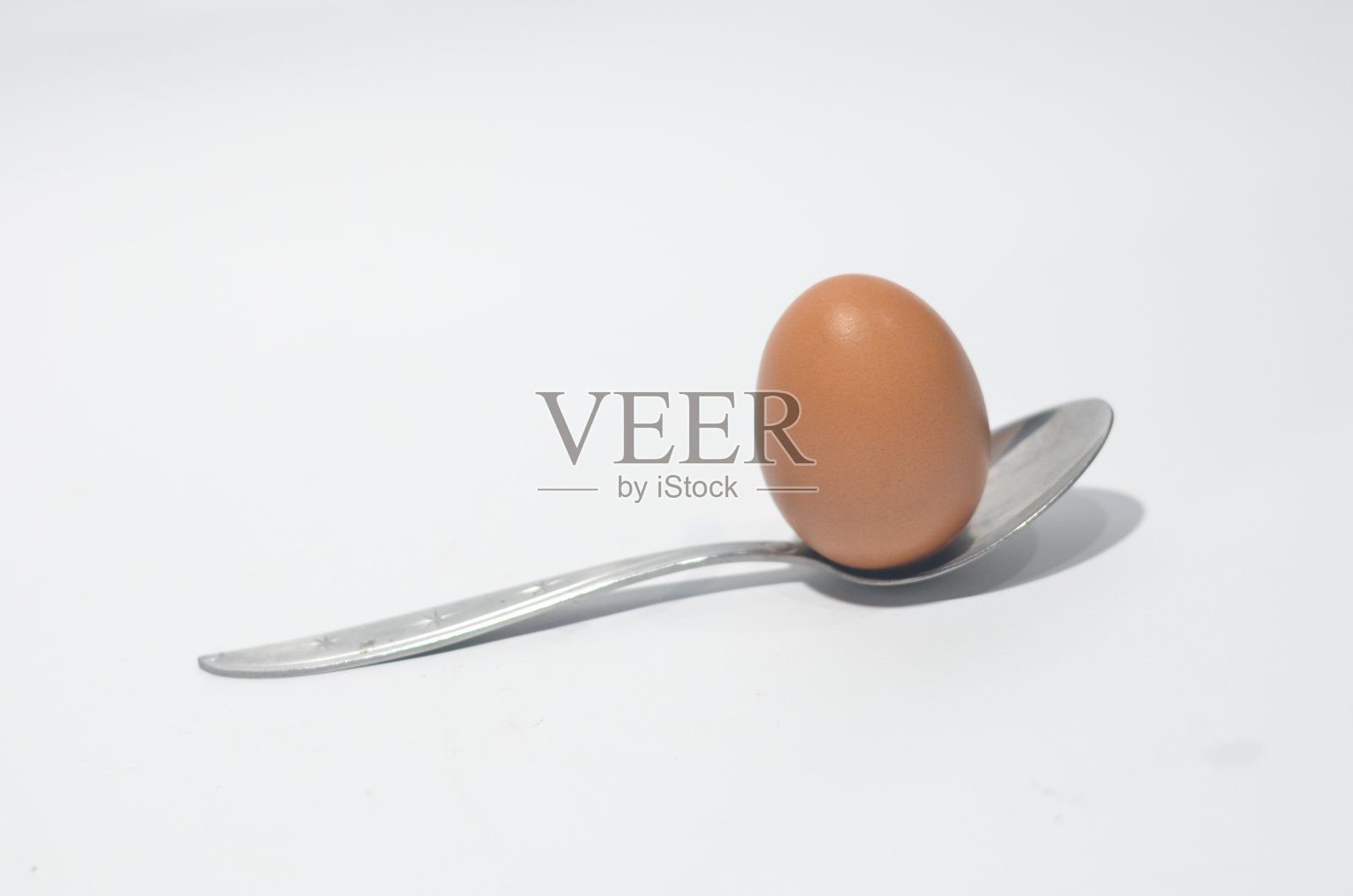 银汤匙与棕色鸡蛋在孤立的白色背景照片摄影图片