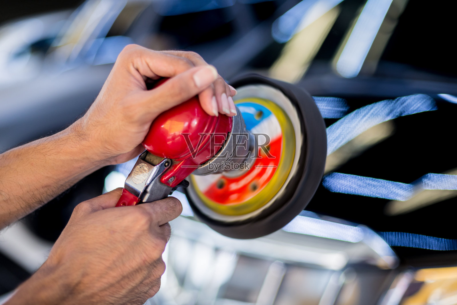 工人用电动工具擦亮汽车。照片摄影图片