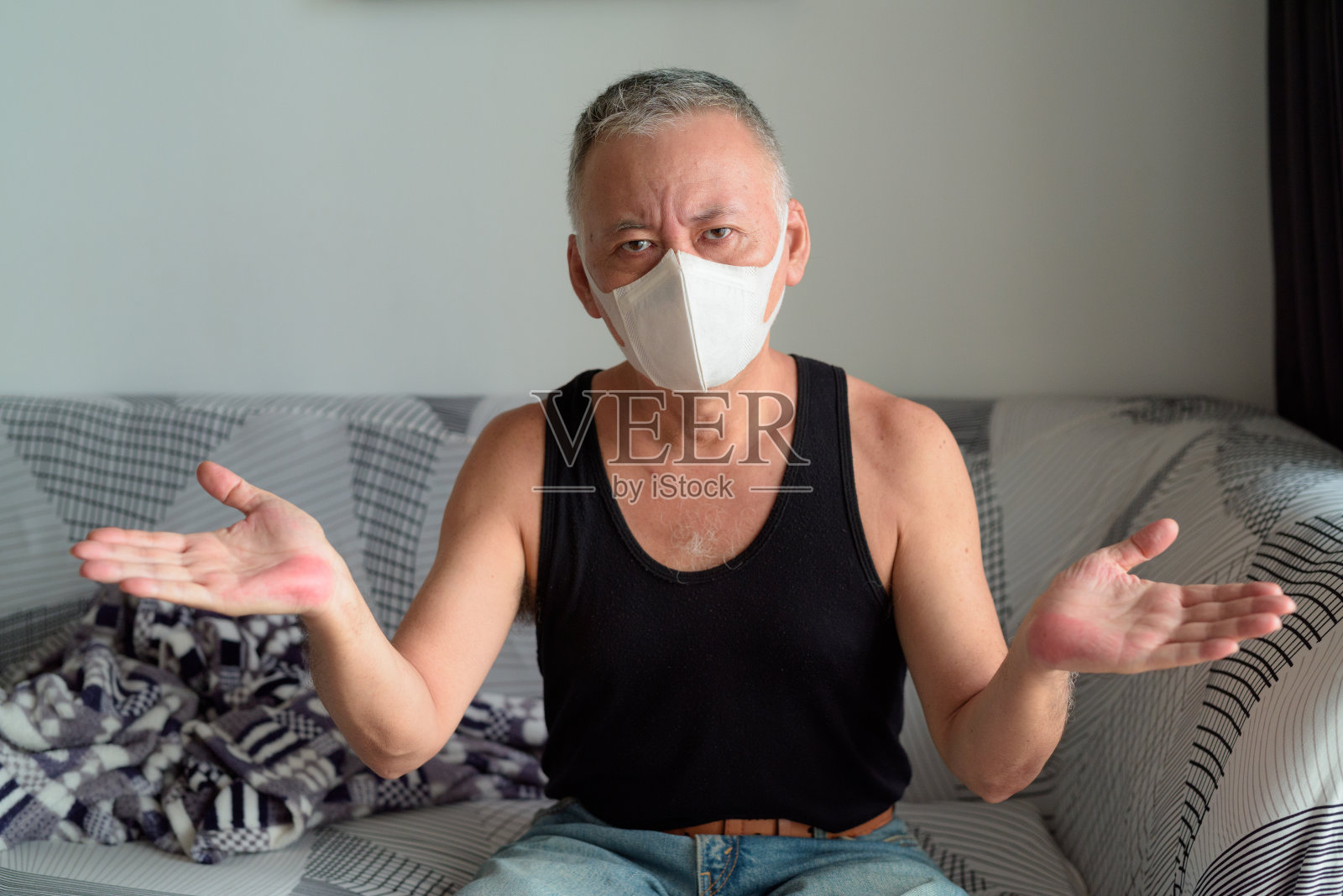 成熟的日本男子带着面具在家中耸肩隔离照片摄影图片