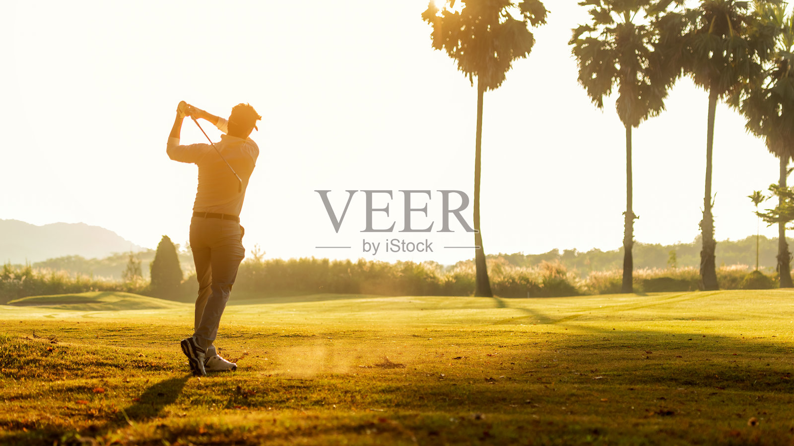 高尔夫球手运动球场高尔夫球道。人们生活方式男人打高尔夫球的高尔夫球tee的在绿色的草地上。亚洲男子玩家游戏拍摄在夏天,阳光的背景。户外健康运动照片摄影图片