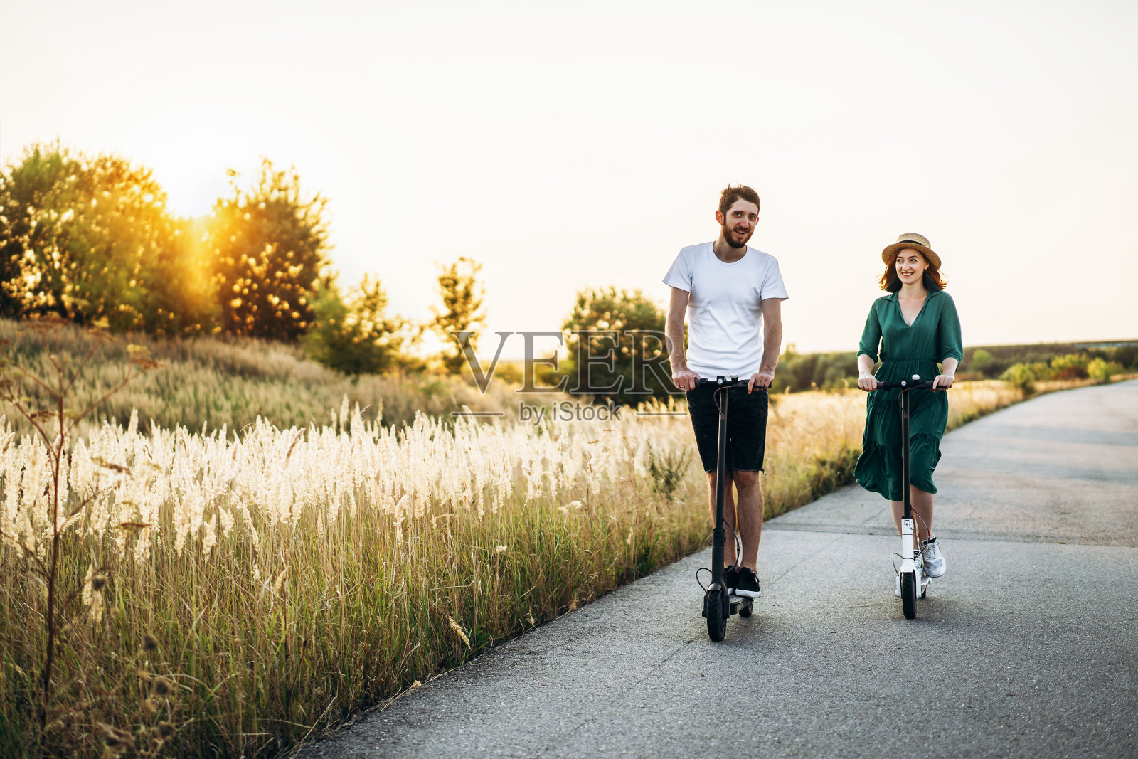 年轻的夫妇度假有乐趣驾驶电动踏板车在乡村的道路上。内容的技术。本空间照片摄影图片