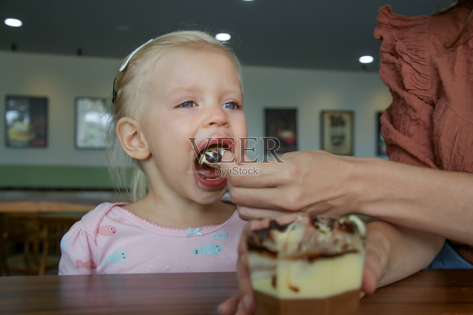 一个蹒跚学步的小女孩在吃巧克力蛋糕。快乐的童年的概念。照片摄影图片