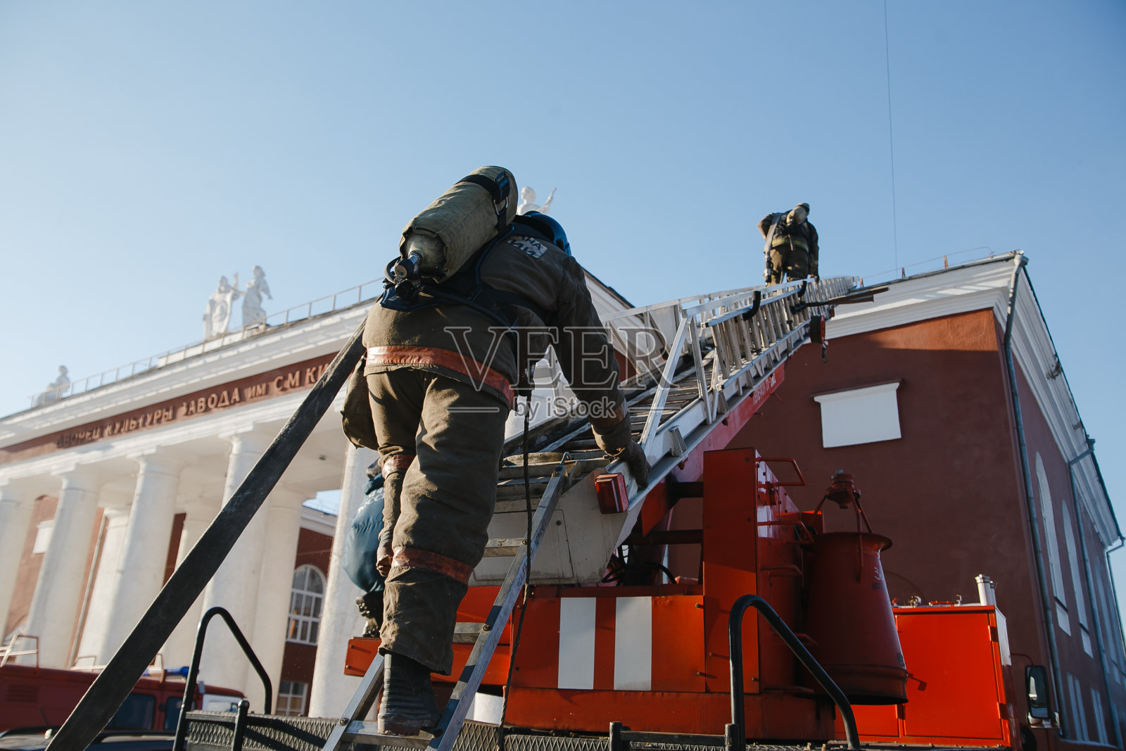 消防队员爬上一百英尺高的梯子。照片摄影图片