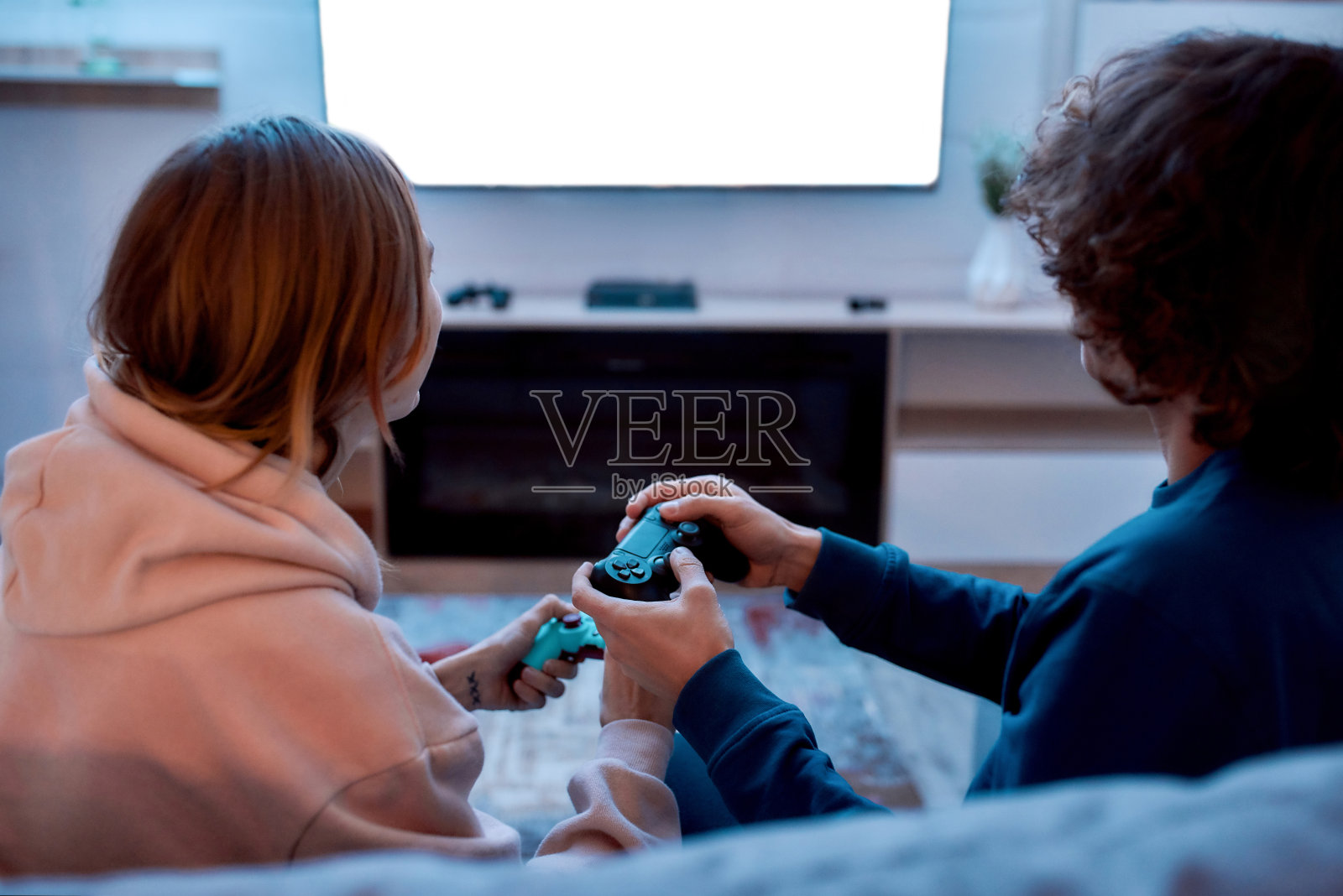 下班后放松。年轻夫妇坐在家里的沙发上玩电子游戏照片摄影图片