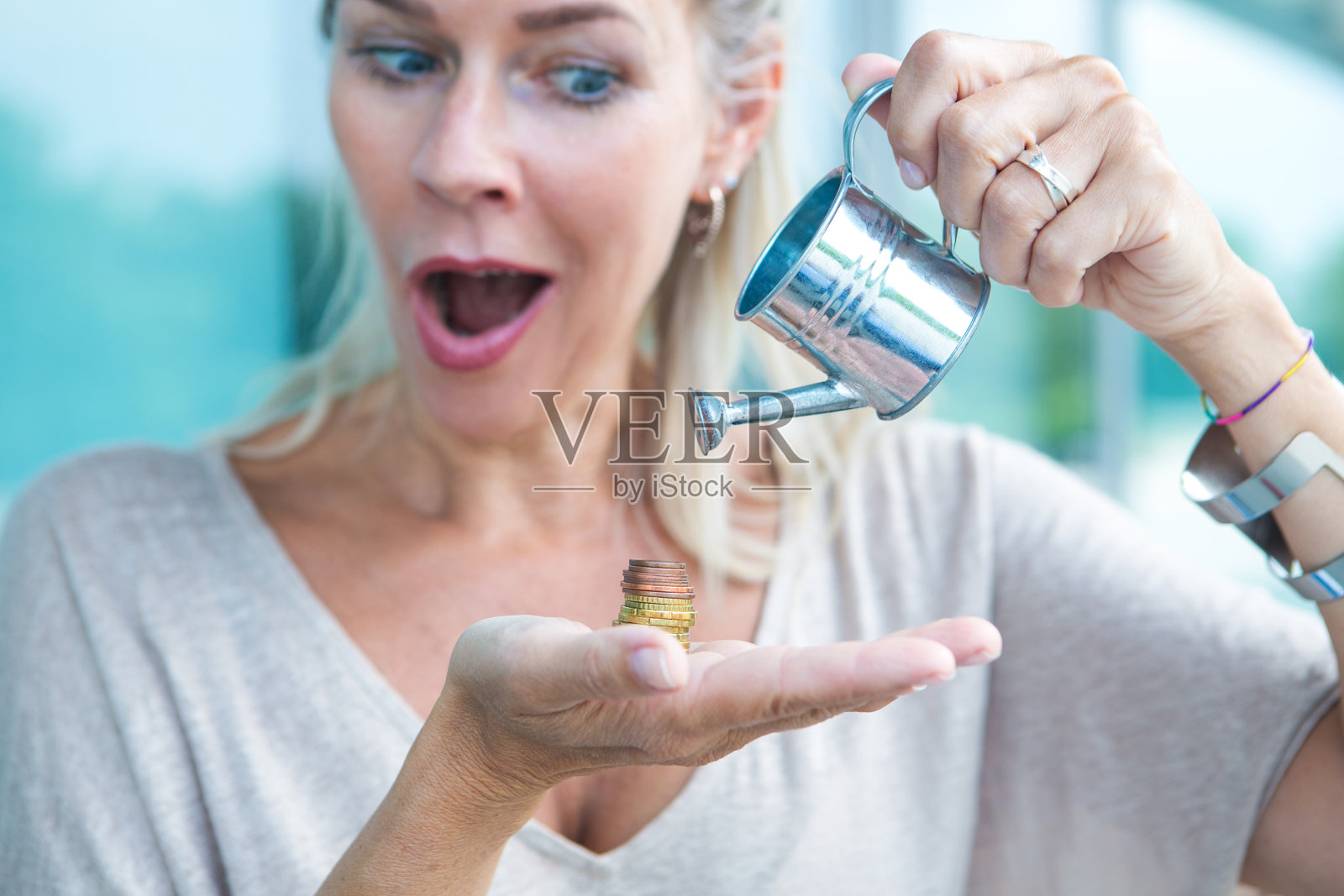 一个金发女人的肖像,拿着硬币,用小罐子浇它们照片摄影图片