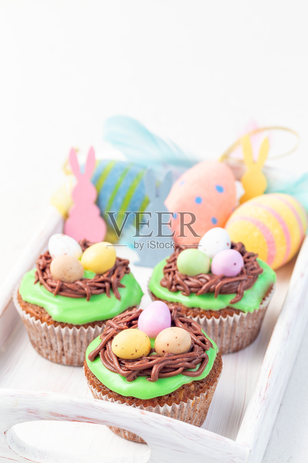 自制胡萝卜松饼装饰奶油芝士糖霜和复活节巧克力蛋,放在木托盘上,垂直照片摄影图片