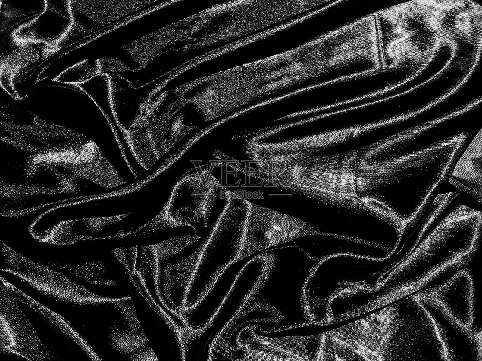 黑色布料或织物纹理背景,带有液体波状或波浪状褶皱。壁纸的设计照片摄影图片