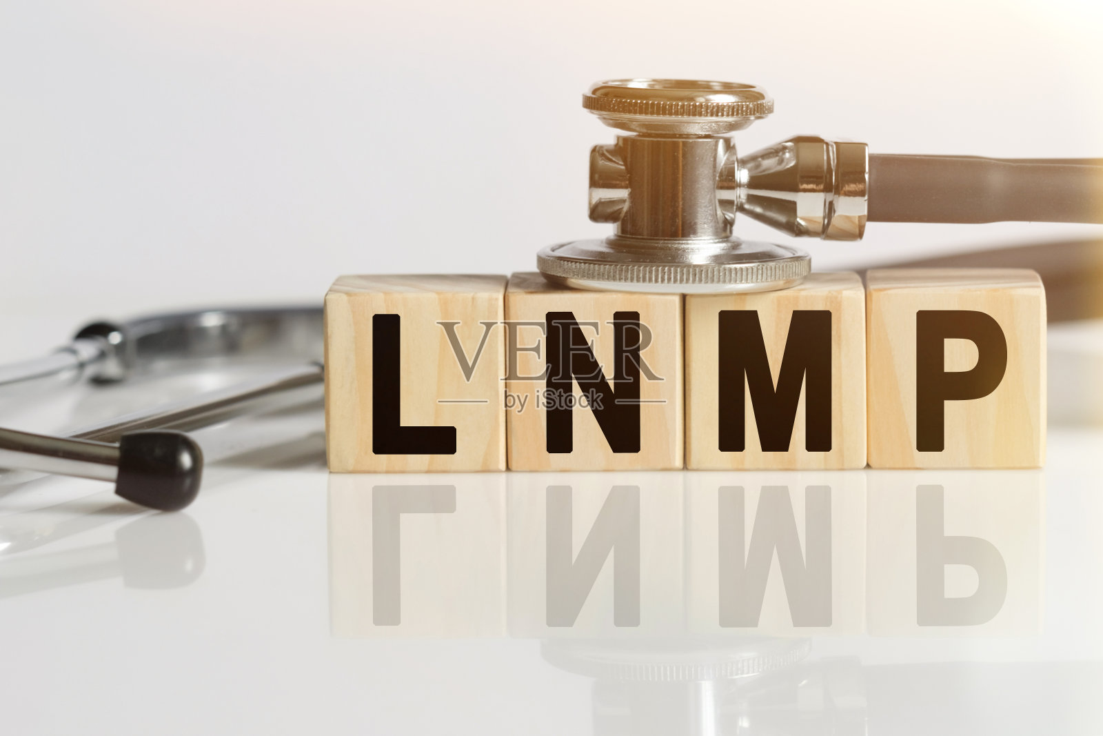 LNMP把字放在木头立方体上,立方体站在反光的白色表面上,立方体上有听诊器。照片摄影图片
