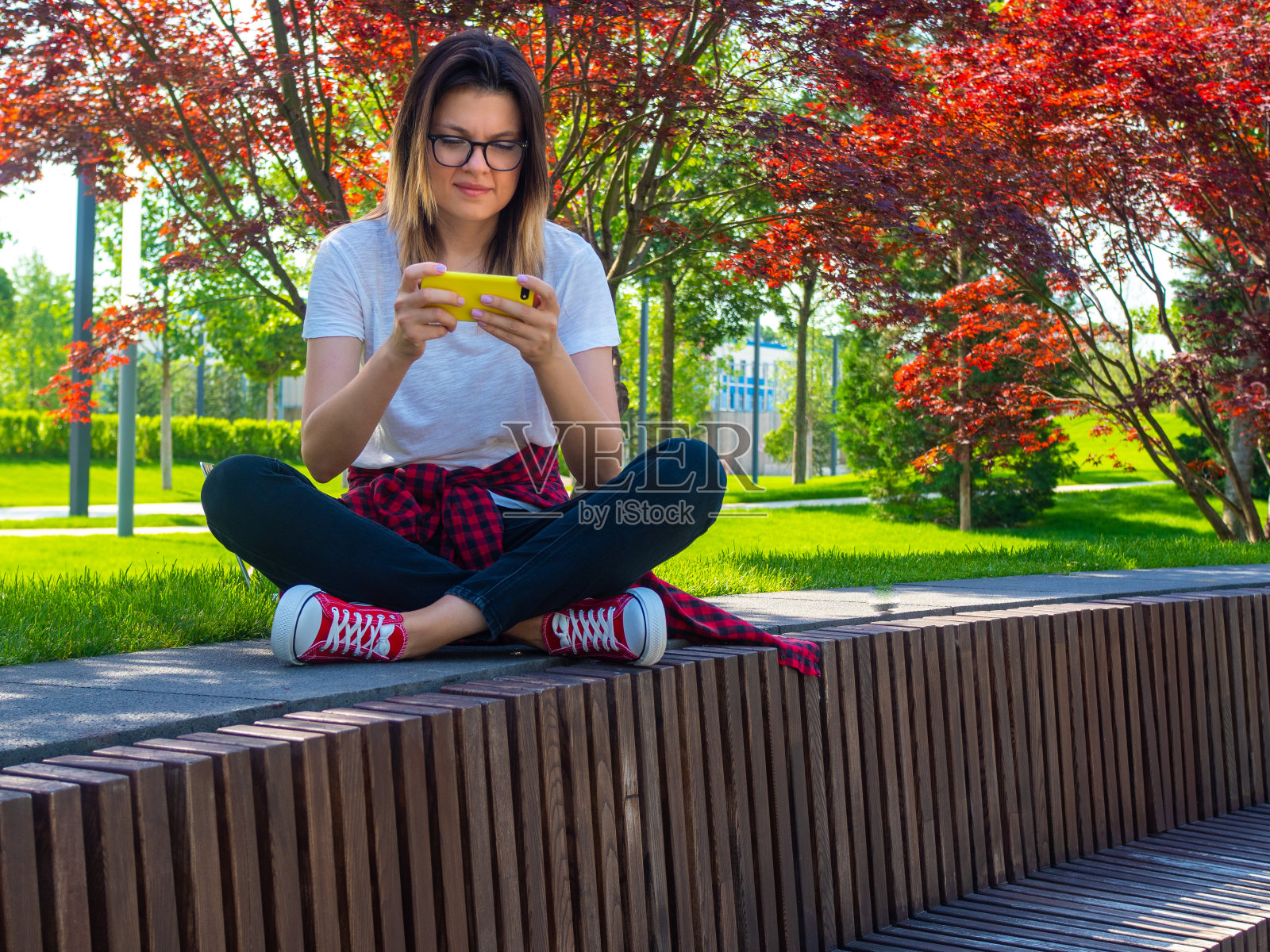 年轻的微笑迷人的女人看黄色智能手机的肖像照片摄影图片