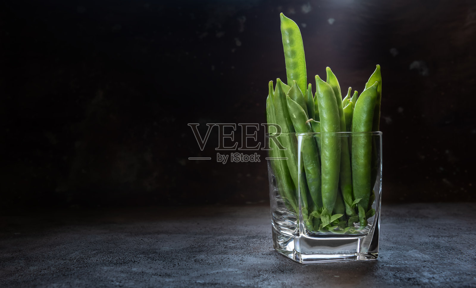 玻璃中的豌豆荚,背景为棕色和灰色照片摄影图片