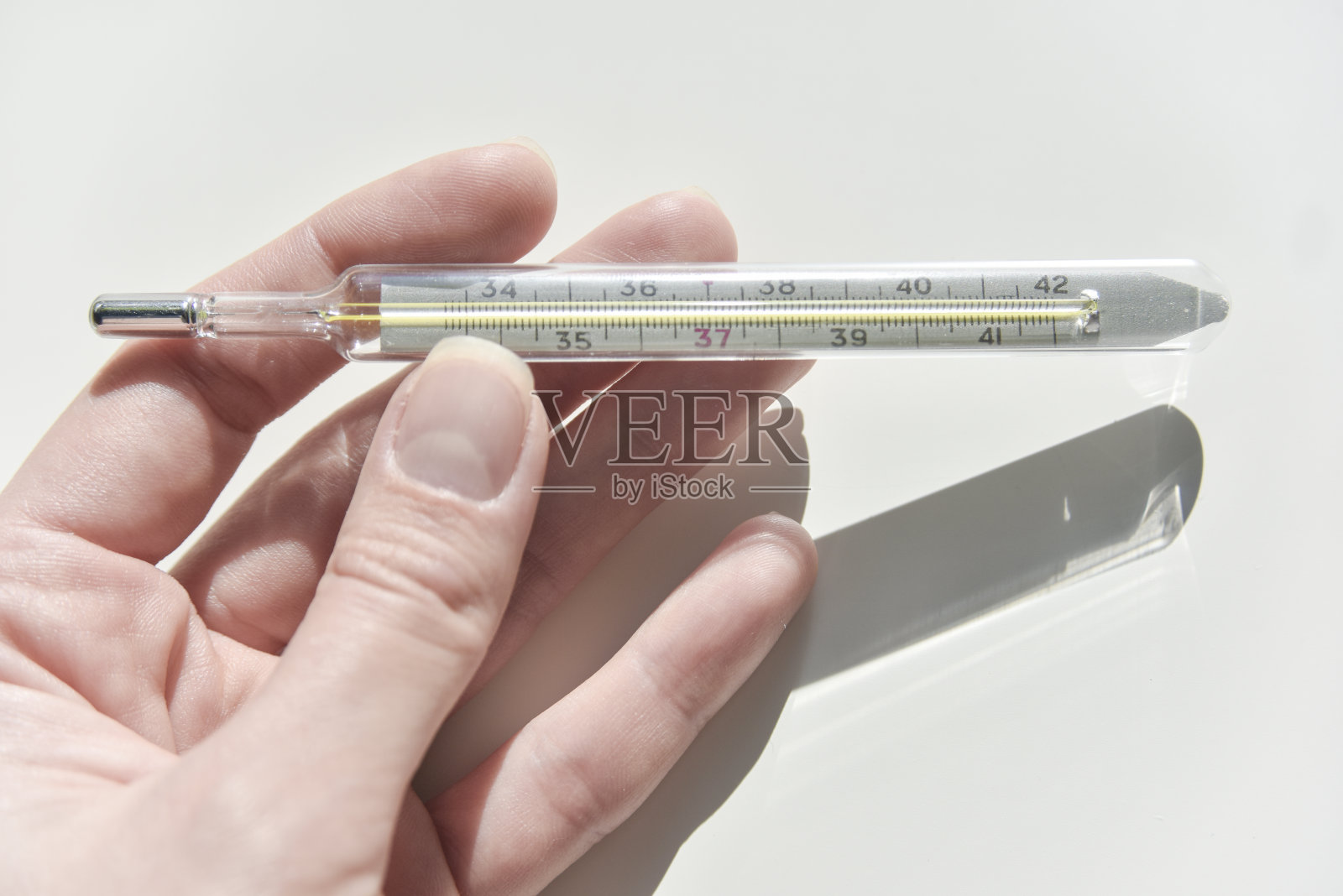 女性手上的体温计上有刻度。健康的概念照片摄影图片