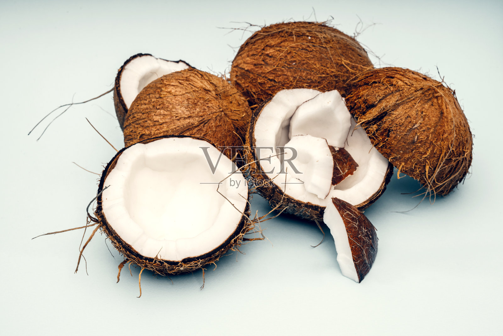 椰子的一部分在一个彩色的背景。关闭了。新鲜成熟的椰子碎成碎片。照片摄影图片