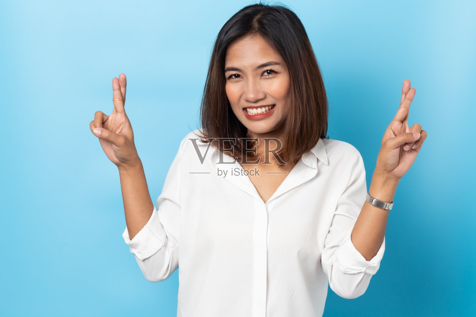 亚洲年轻女子与手指交叉孤立在蓝色背景照片摄影图片
