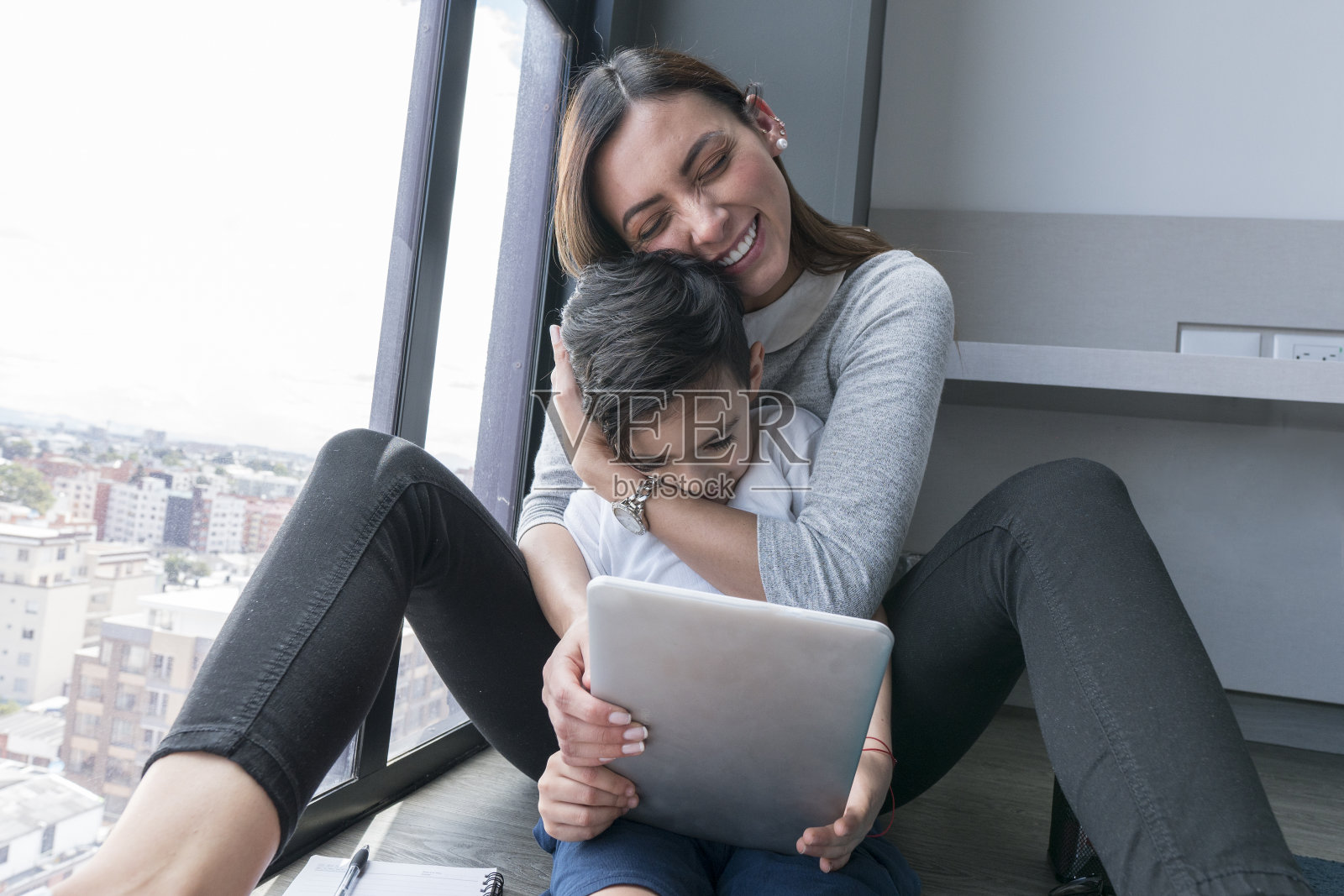 一位年轻的拉丁美洲妇女陪着她的儿子上虚拟课程照片摄影图片