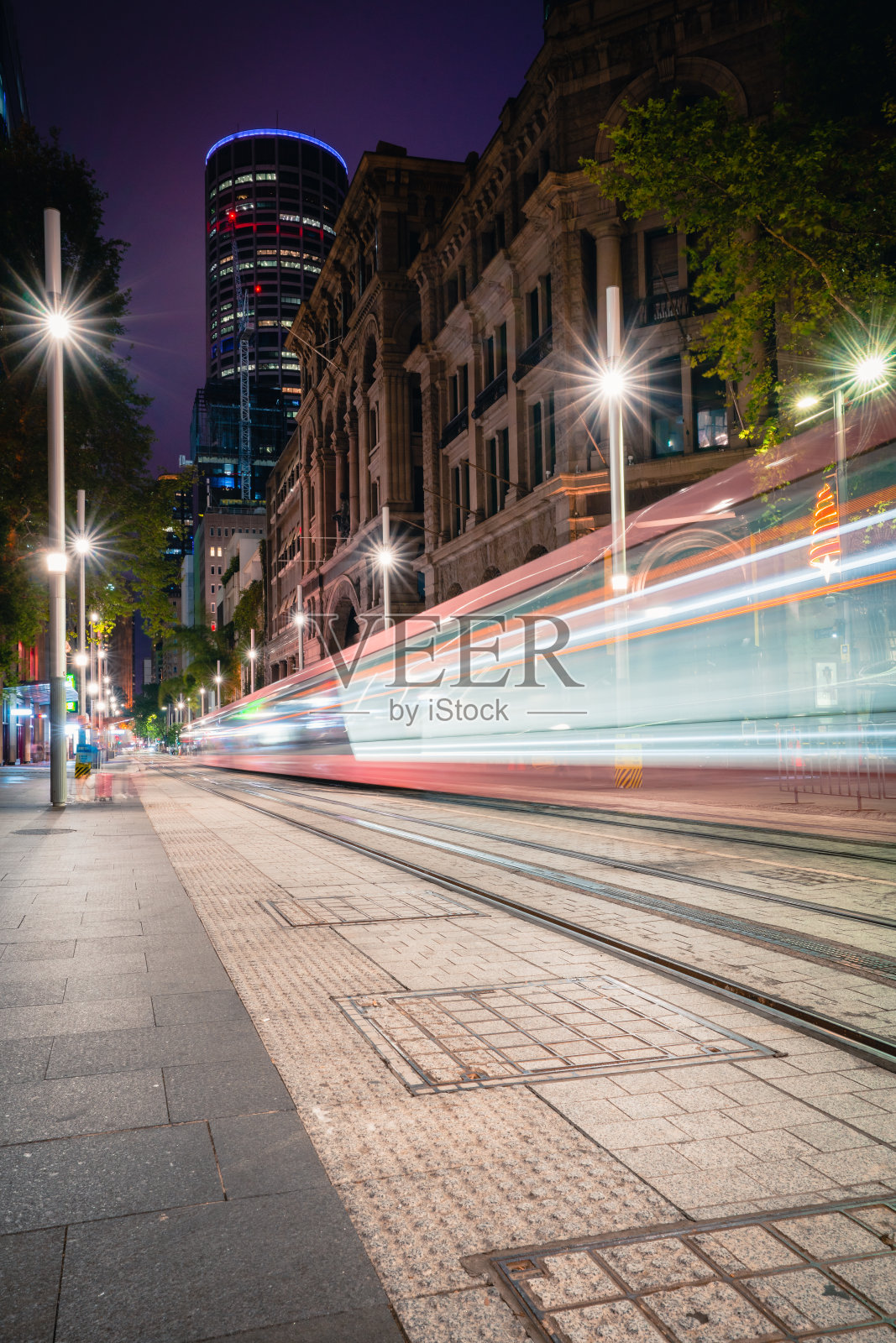 沿着繁忙的城市街道中心行驶的轻轨电车照片摄影图片