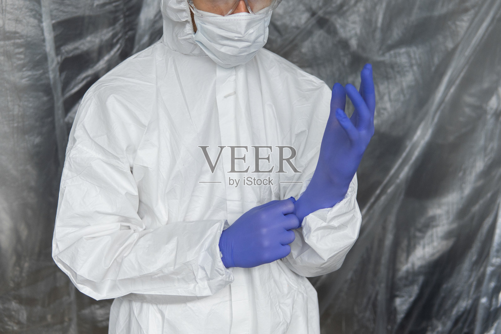 在冠状病毒大流行威胁下,身着白色防护服、口罩、眼镜和橡胶手套的医生随时准备帮助人民。疫情,新冠肺炎大流行。医生在呼吸器。照片摄影图片