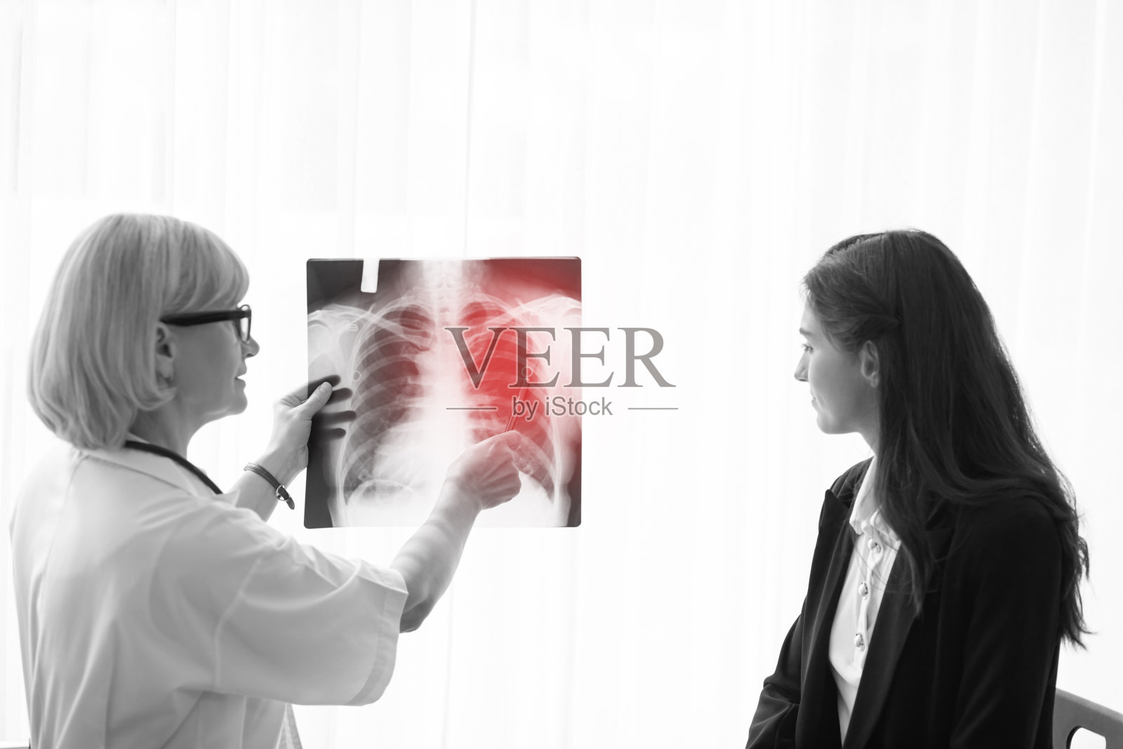 医生正在医院和病人一起研究肺结核x光片。照片摄影图片