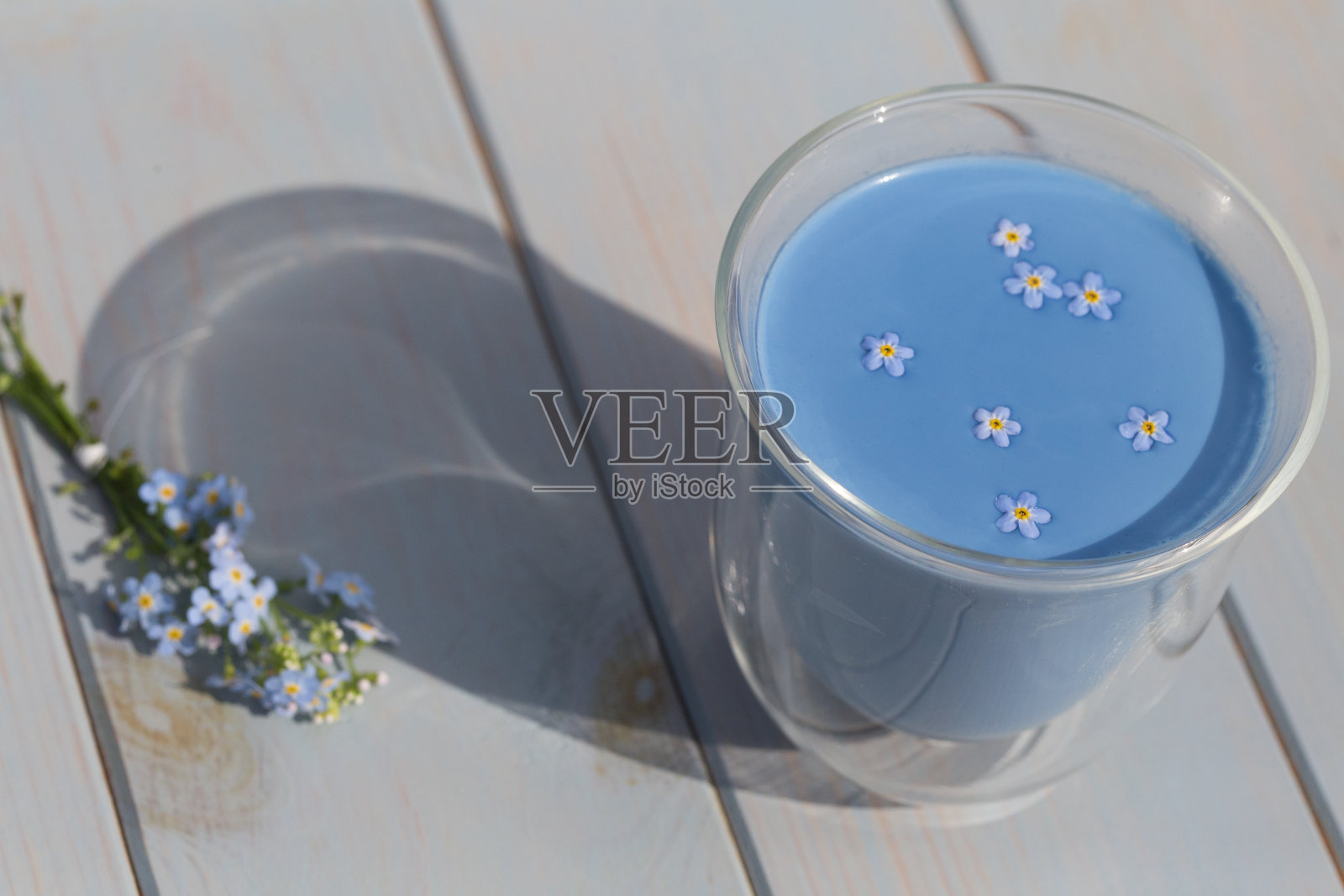 蓝色抹茶拿铁安禅和勿忘我在玻璃杯站在蓝色木桌照片摄影图片