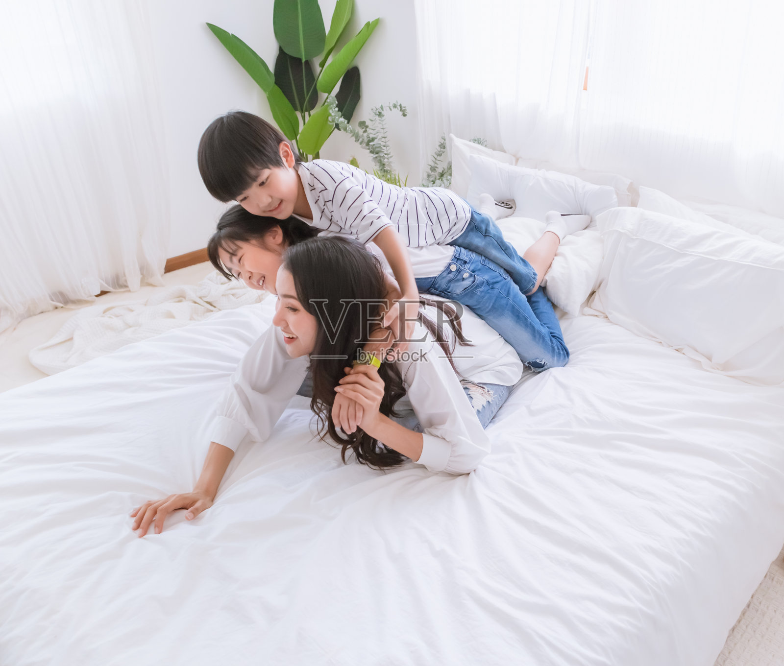 可爱幸福的亚洲家庭在舒适的家。微笑的母亲,儿子和女儿享受,放松和玩耍在卧室里。父母和孩子之间的幸福关系和爱的纽带时刻照片摄影图片