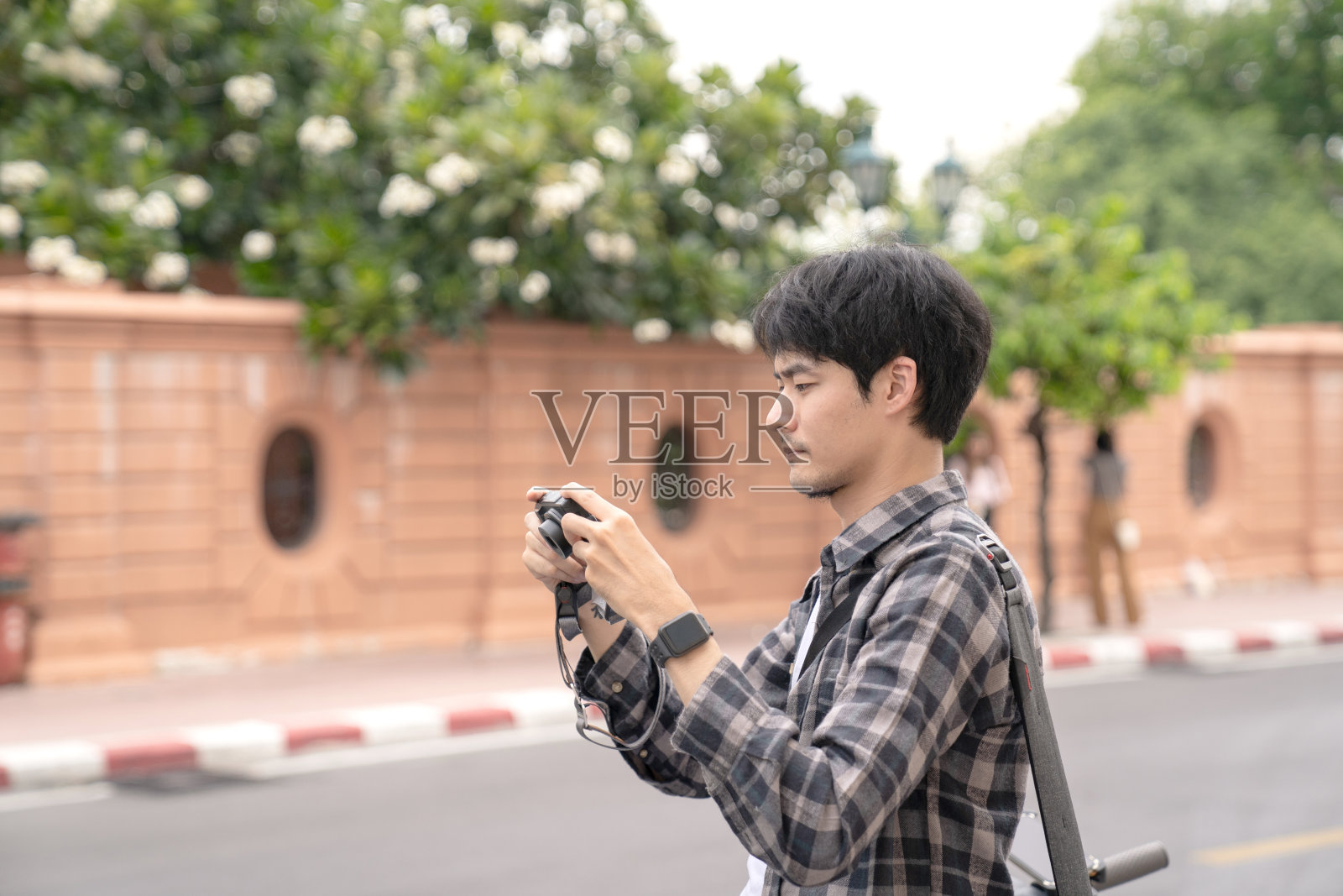 一名年轻游客拿着相机拍照。照片摄影图片